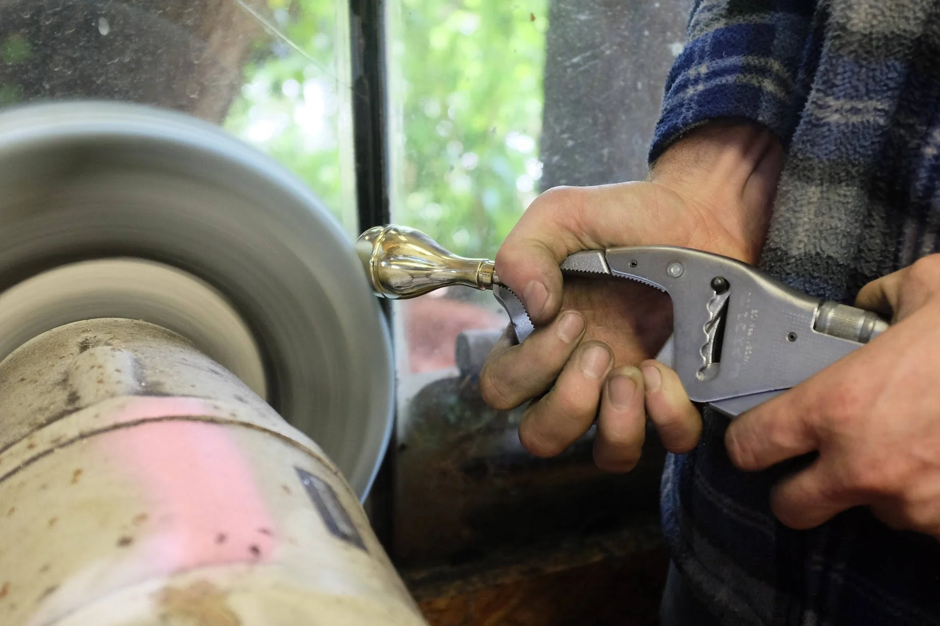 Une personne utilisant un tournevis pour façonner ou polir un objet en verre sur une machine de tournage de verre.