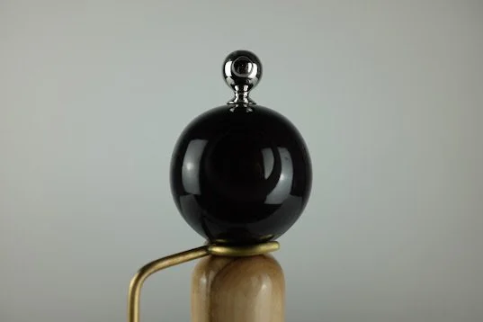 Une bille noire posée sur une petite plateforme en bois avec un support en métal