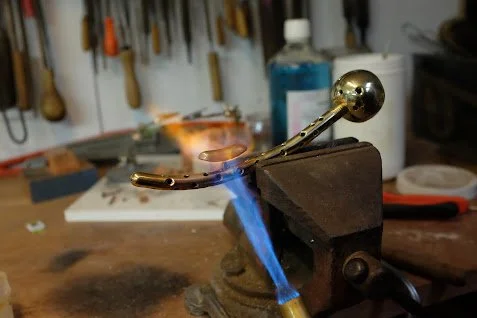 Une pièce de métal en forme de boule fixée dans un étau de travail.