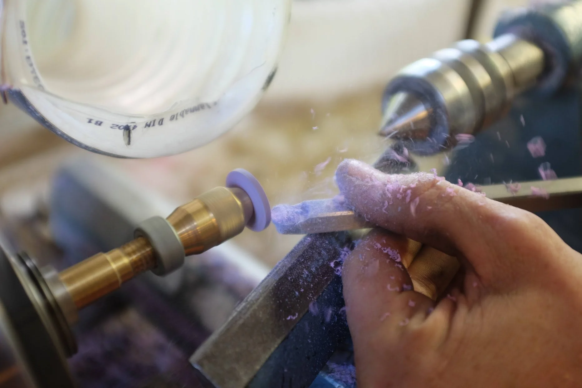 Une personne tourne une pièce en bois sur un tour à bois, avec des copeaux de bois volant dans l'air, à l'aide d'un outil de sculpture.
