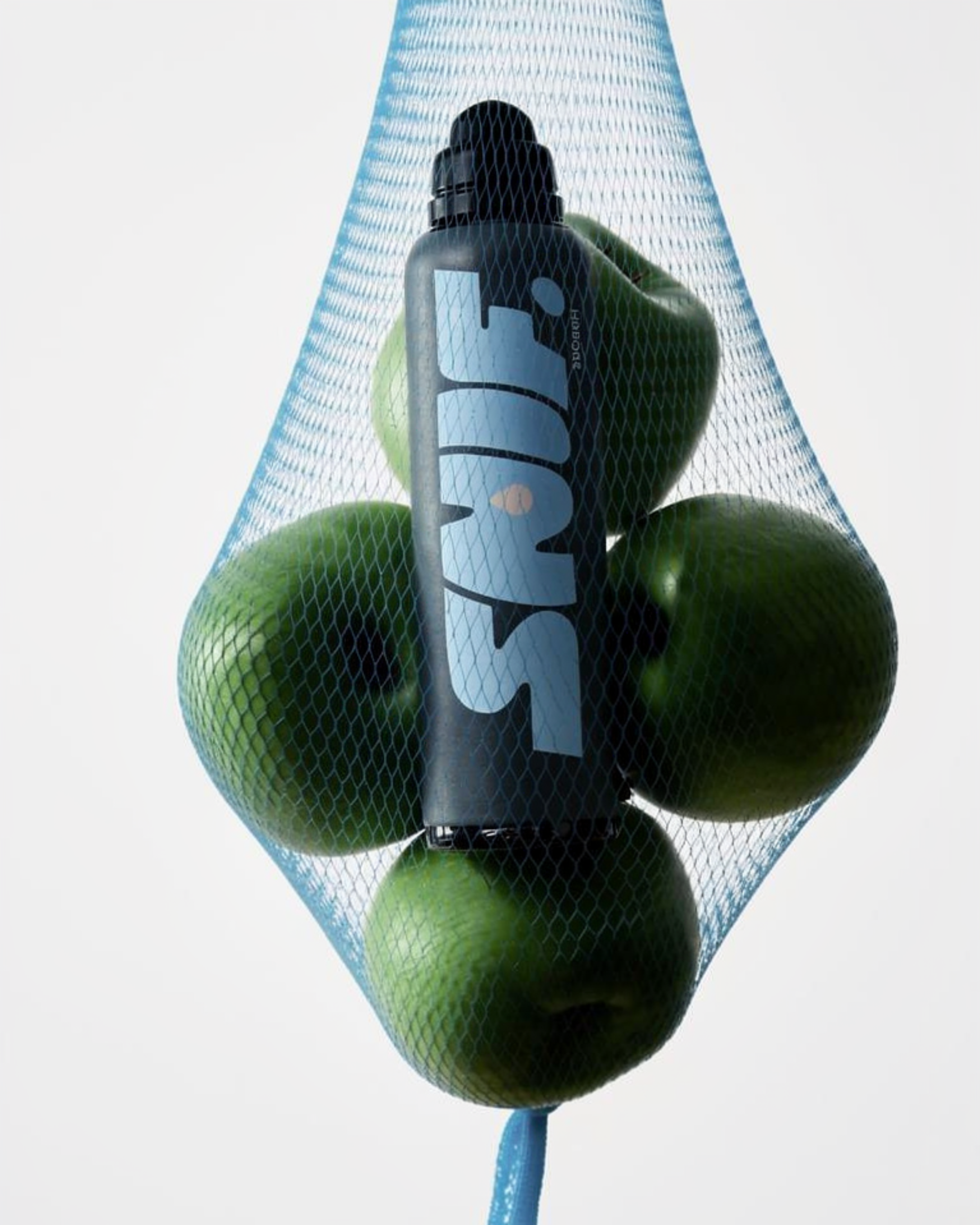 Groene appels in een blauw net, met een flesje met het label 'SMASH' tussen de appels.