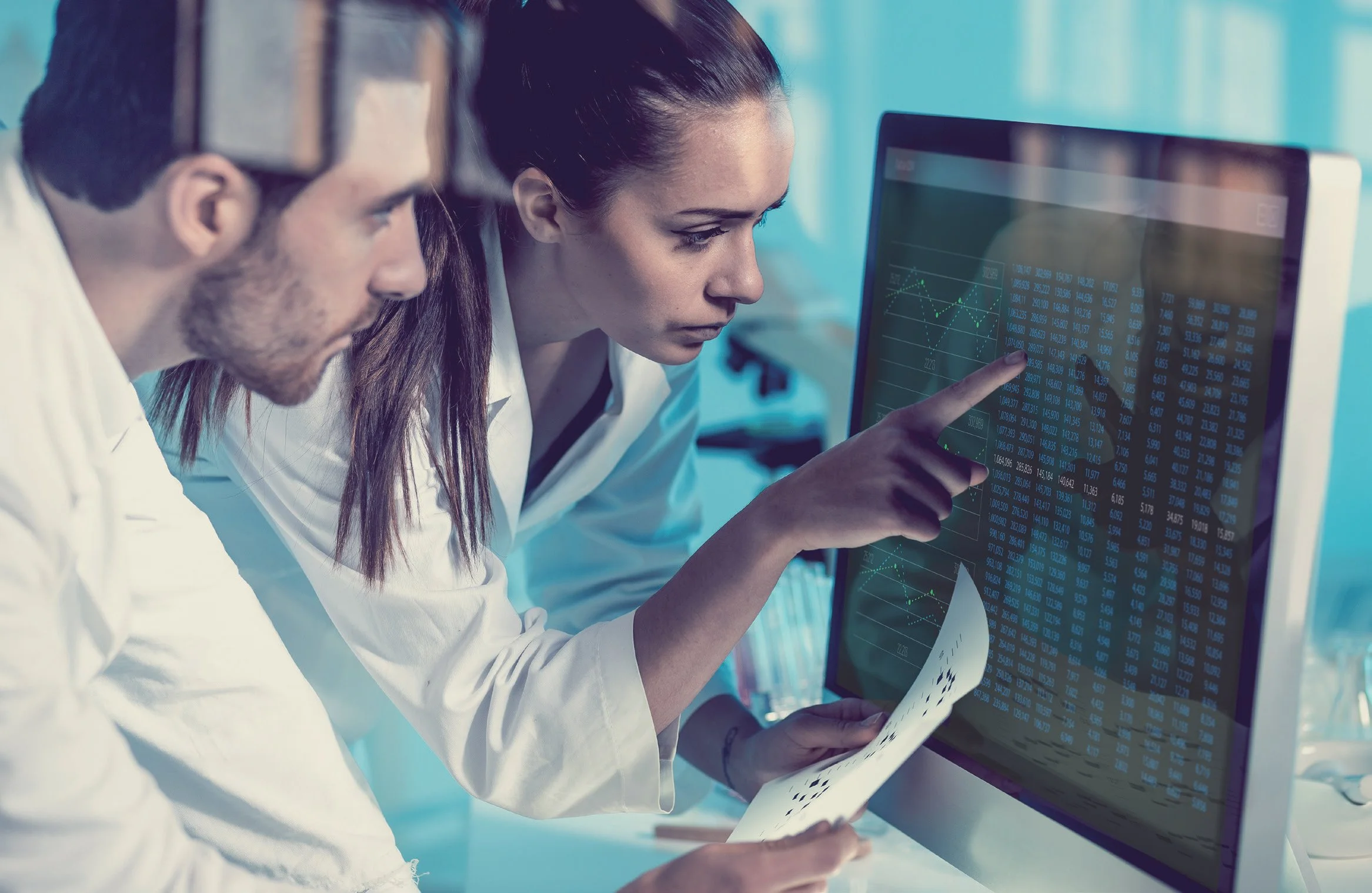 Two scientists analyzing data on a computer screen in a laboratory.