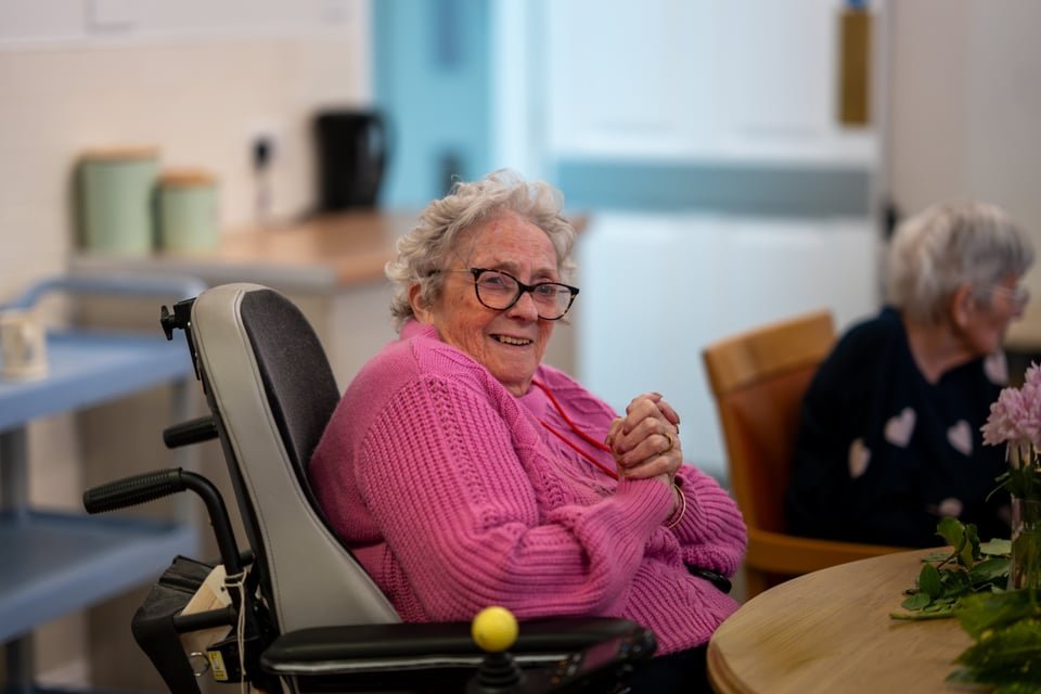 happy lady sat in care home