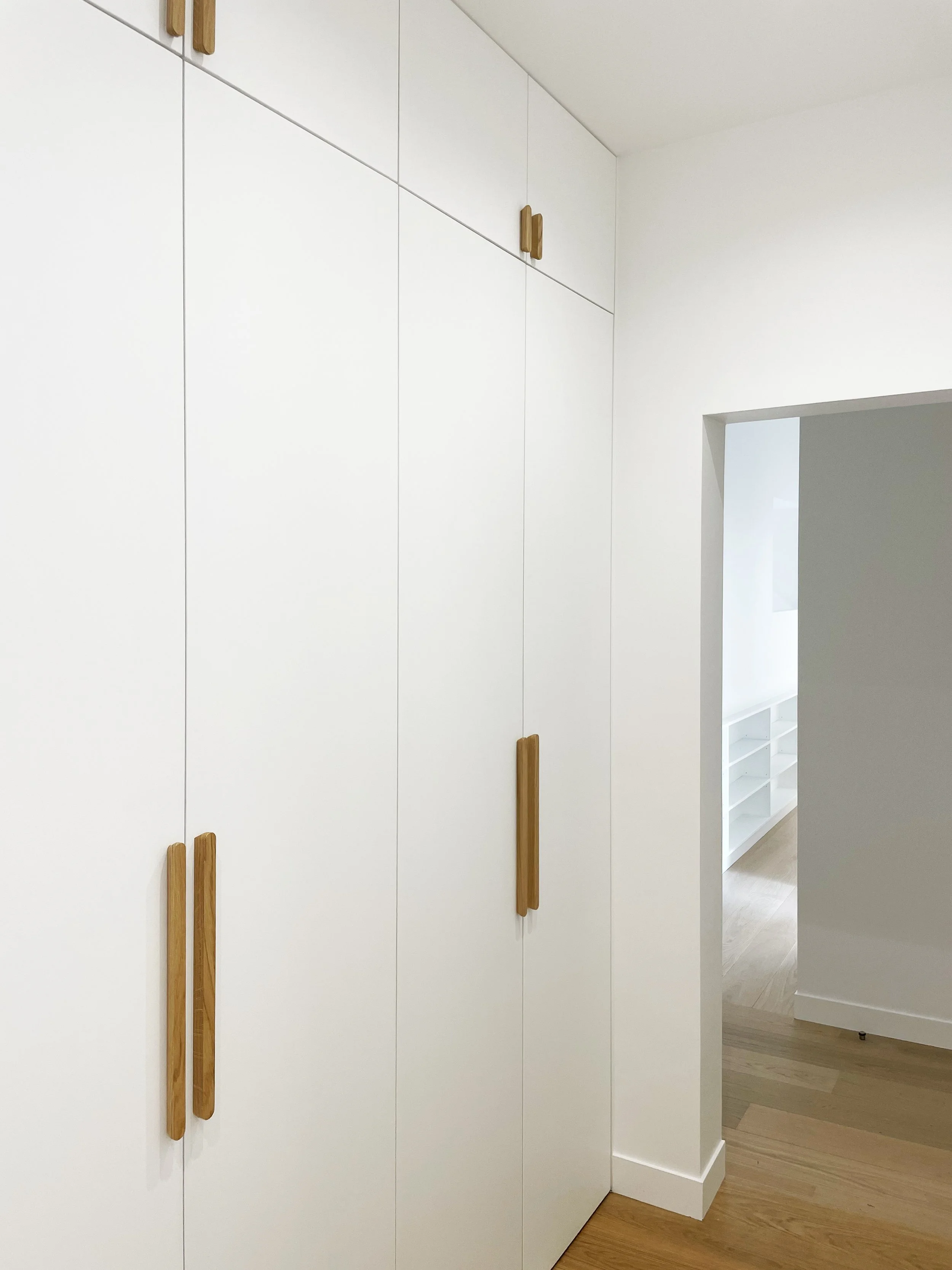 Placard blanc avec poignées en bois dans une pièce moderne.