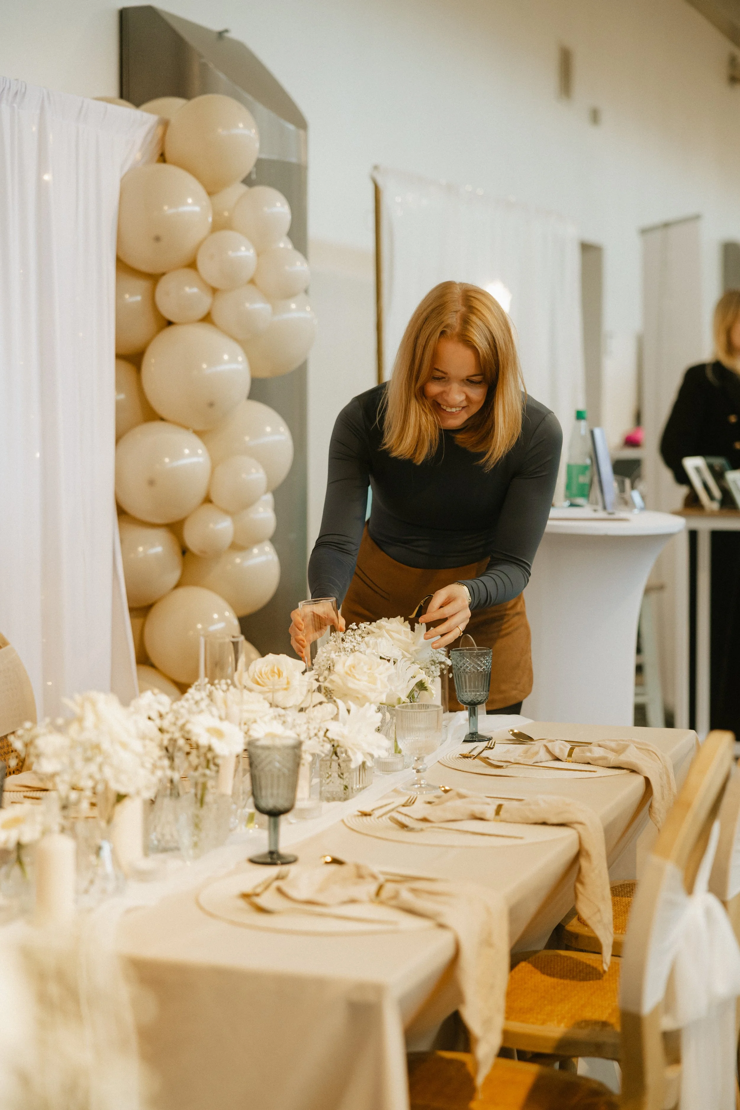 Blumenarrangement an einer festlich gedeckten Eventtafel mit Kerzen und Gläsern.