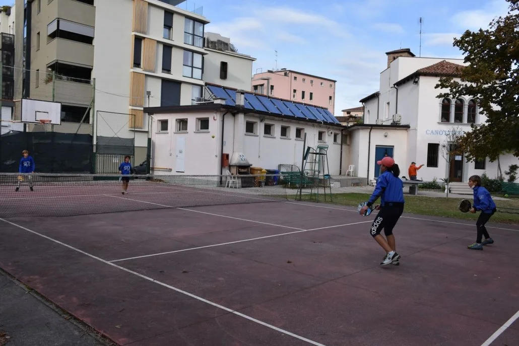 Bambini che giocano a tennis su un campo all'aperto in un'area urbana