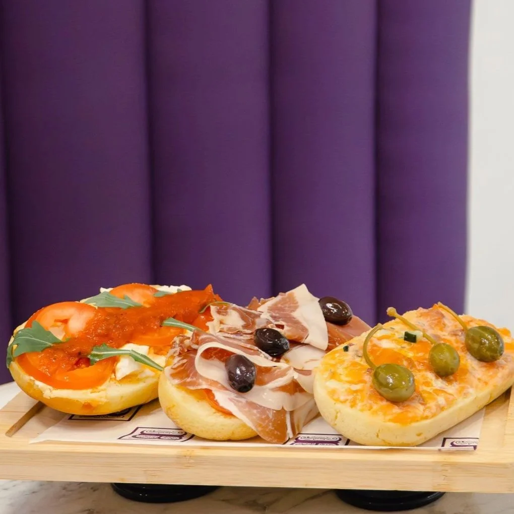 Tres mini pizzas con diferentes ingredientes sobre una tabla de madera.