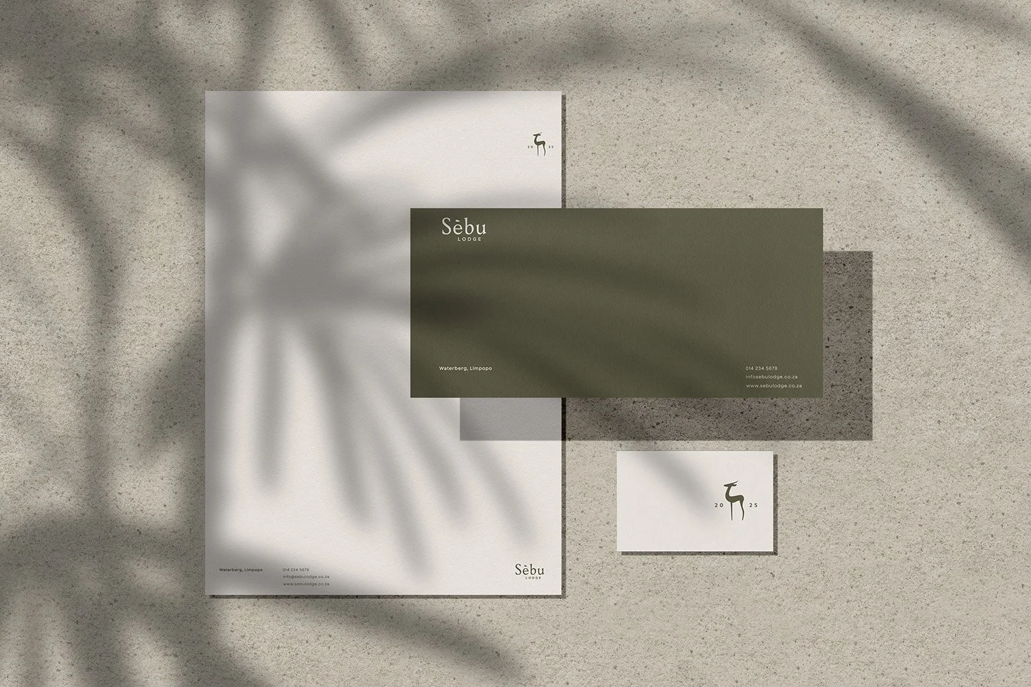 Business stationery set for Sebu Lodge, including letterhead, business card, and envelope, placed on a concrete surface with shadows of leaves.