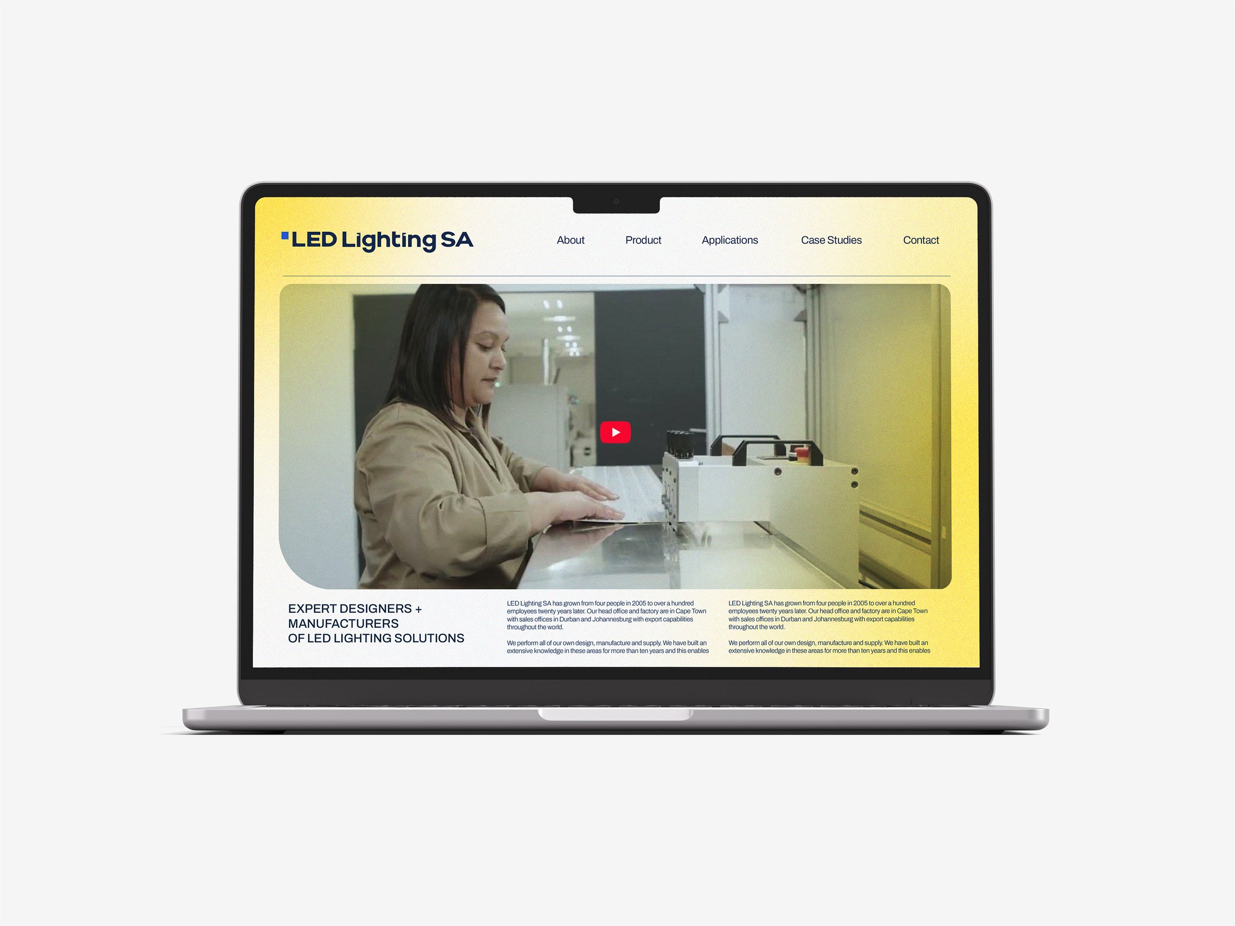 Laptop displaying a website for LED Lighting SA, featuring an image of a woman working with LED lighting equipment in a factory setting, with navigation menu and text descriptions.