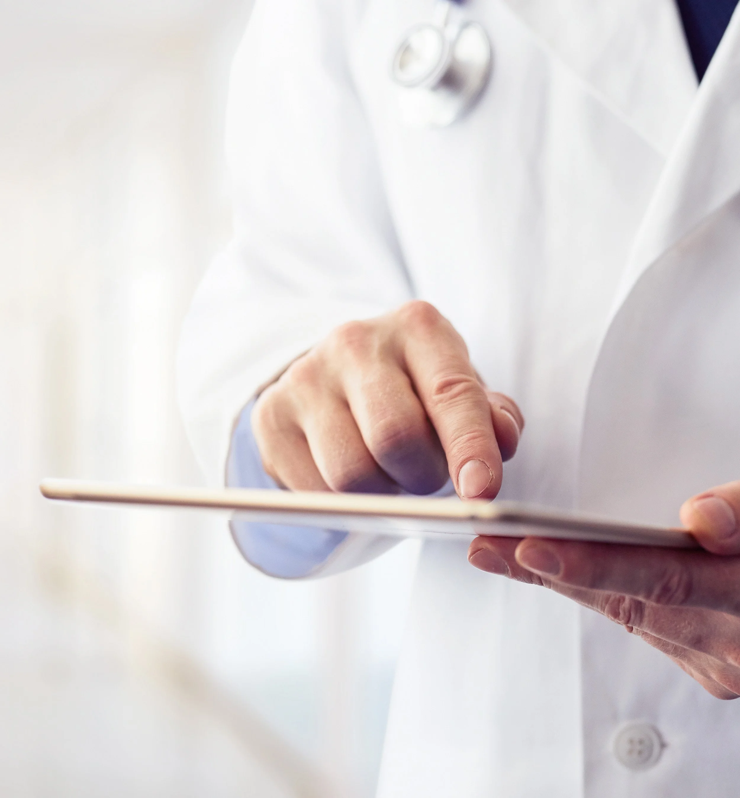 Medical professional in a white coat using a tablet.