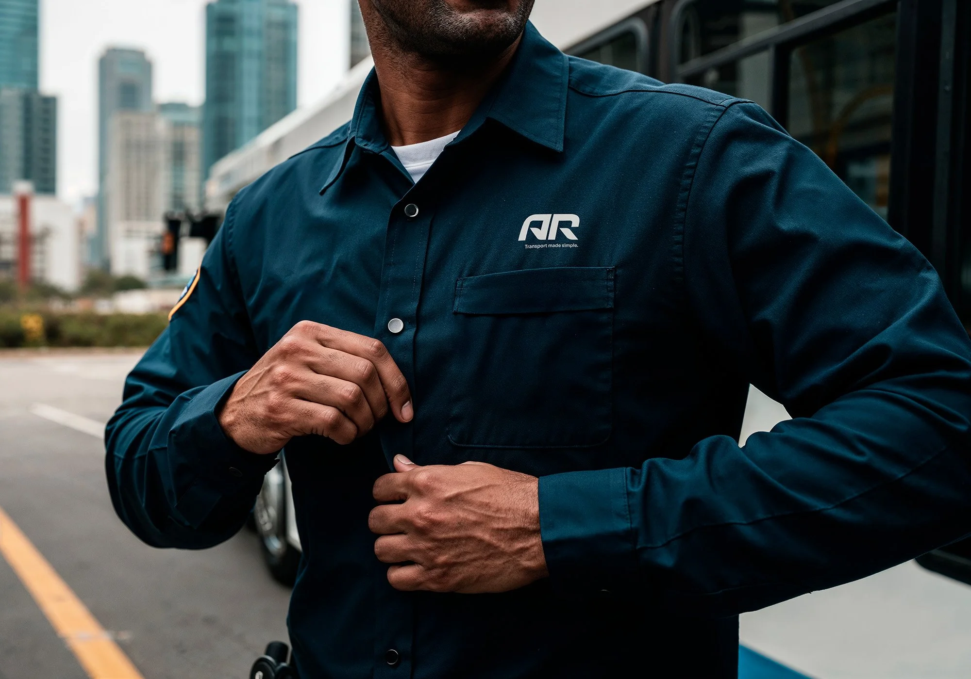 A man in a dark blue uniform with the logo 'ARC' on the chest, standing on a city street, adjusting his shirt.