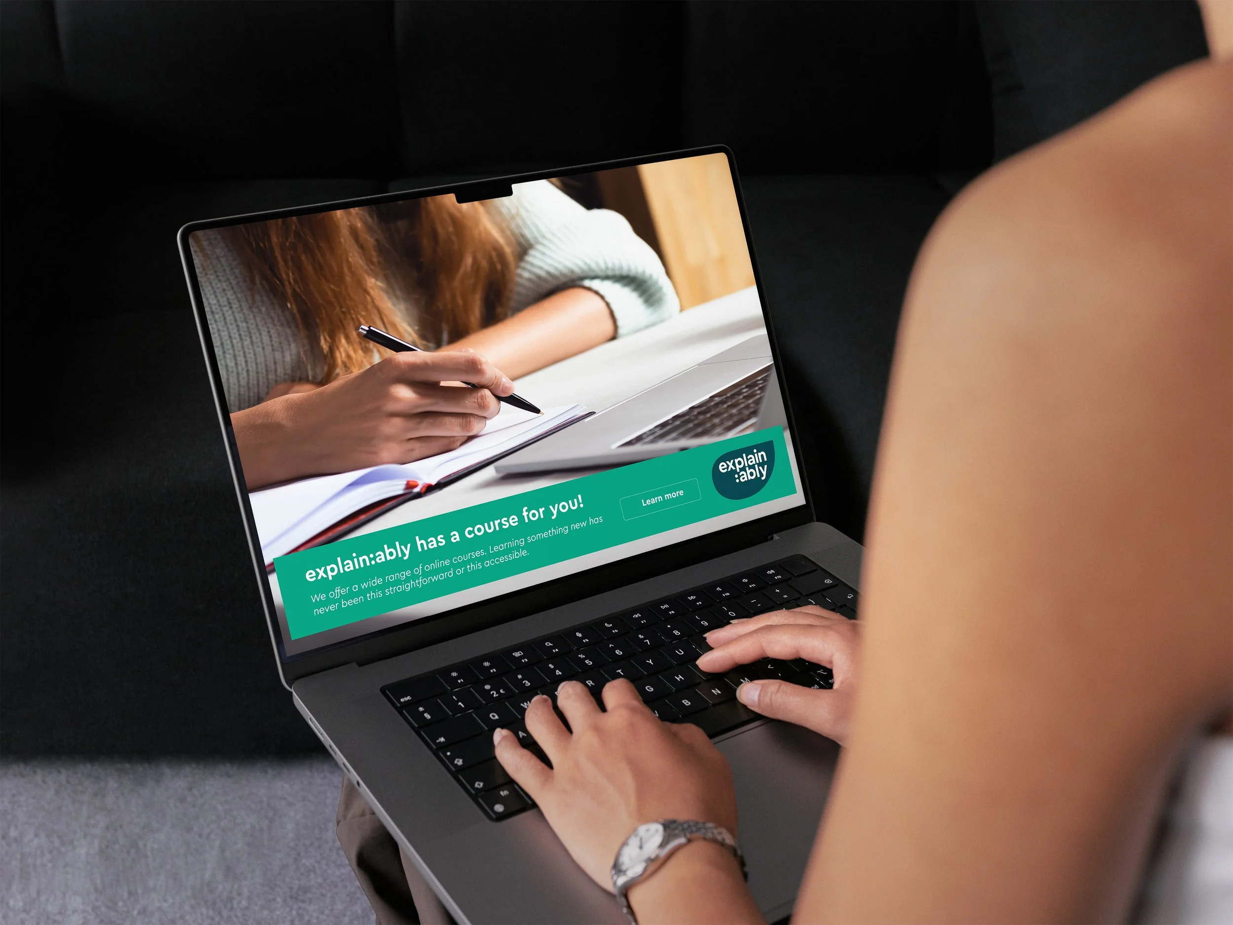 Girl on a Macbook scrolling through the Explain:ably website. A pop-up advertisement offer you a online course to join and explore.