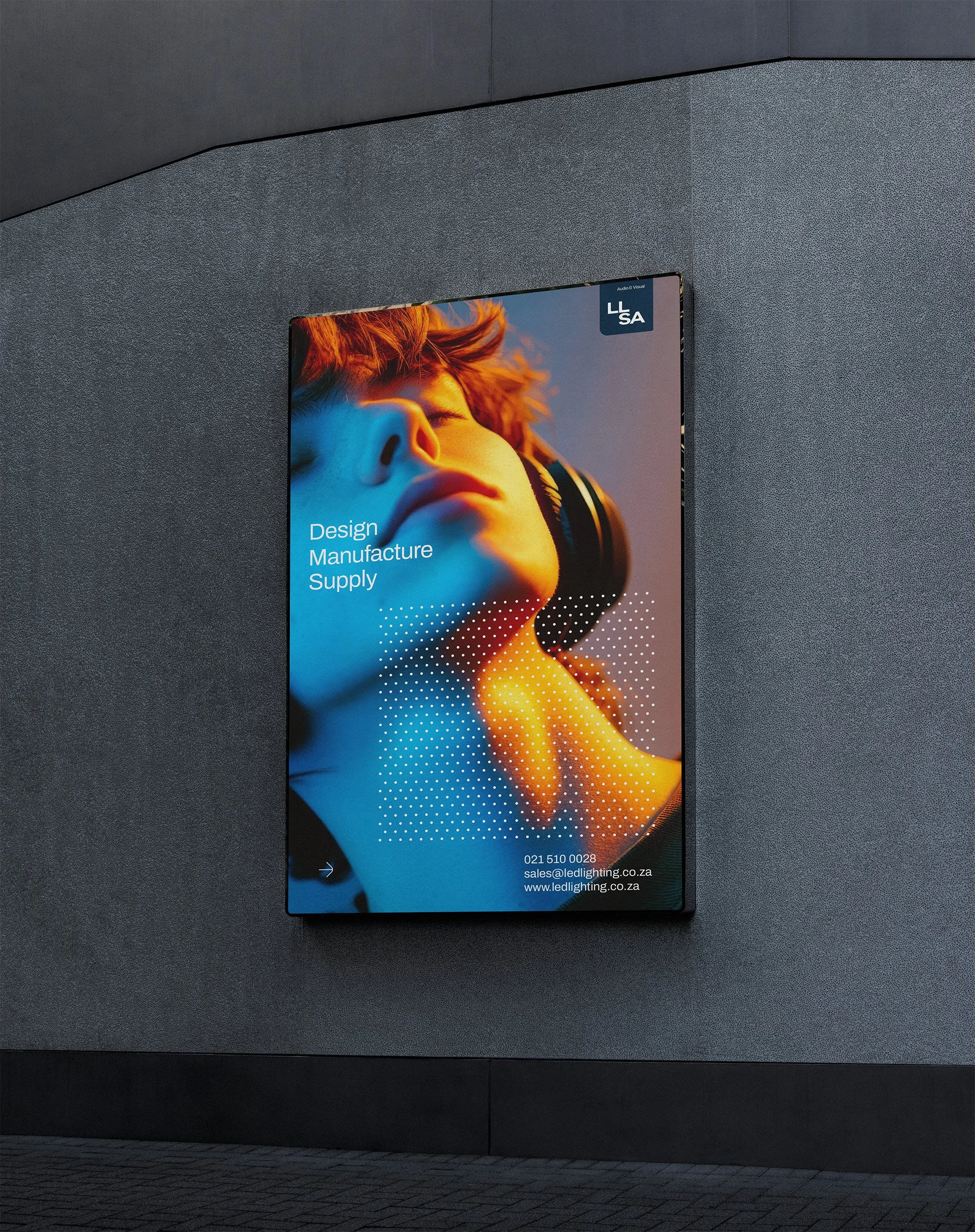 A large, framed advertisement for a company called LED Lighting, featuring a close-up of a person wearing headphones and touching their neck, with the words "Design, Manufacture, Supply" and contact information at the bottom.