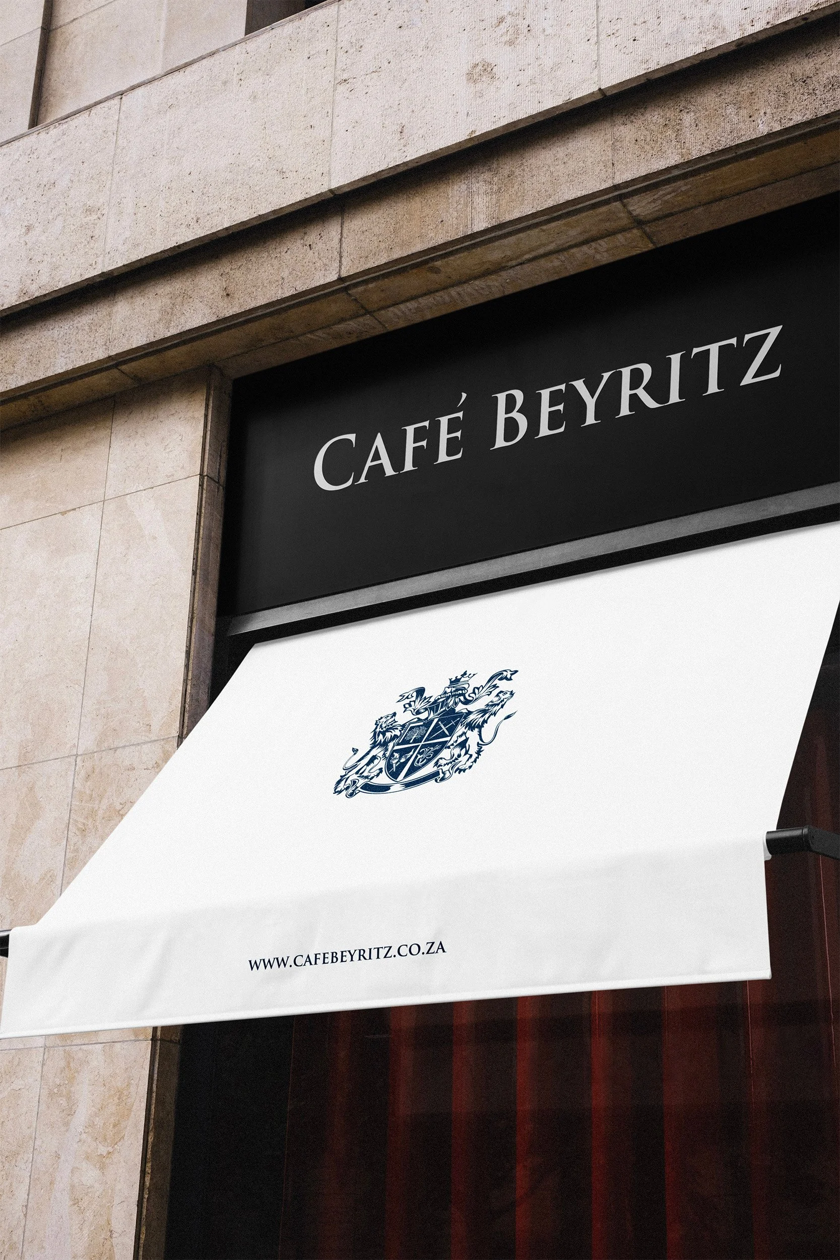 A sign for Café Beyritz featuring a black background with white text, and a white awning with a crest and website URL.