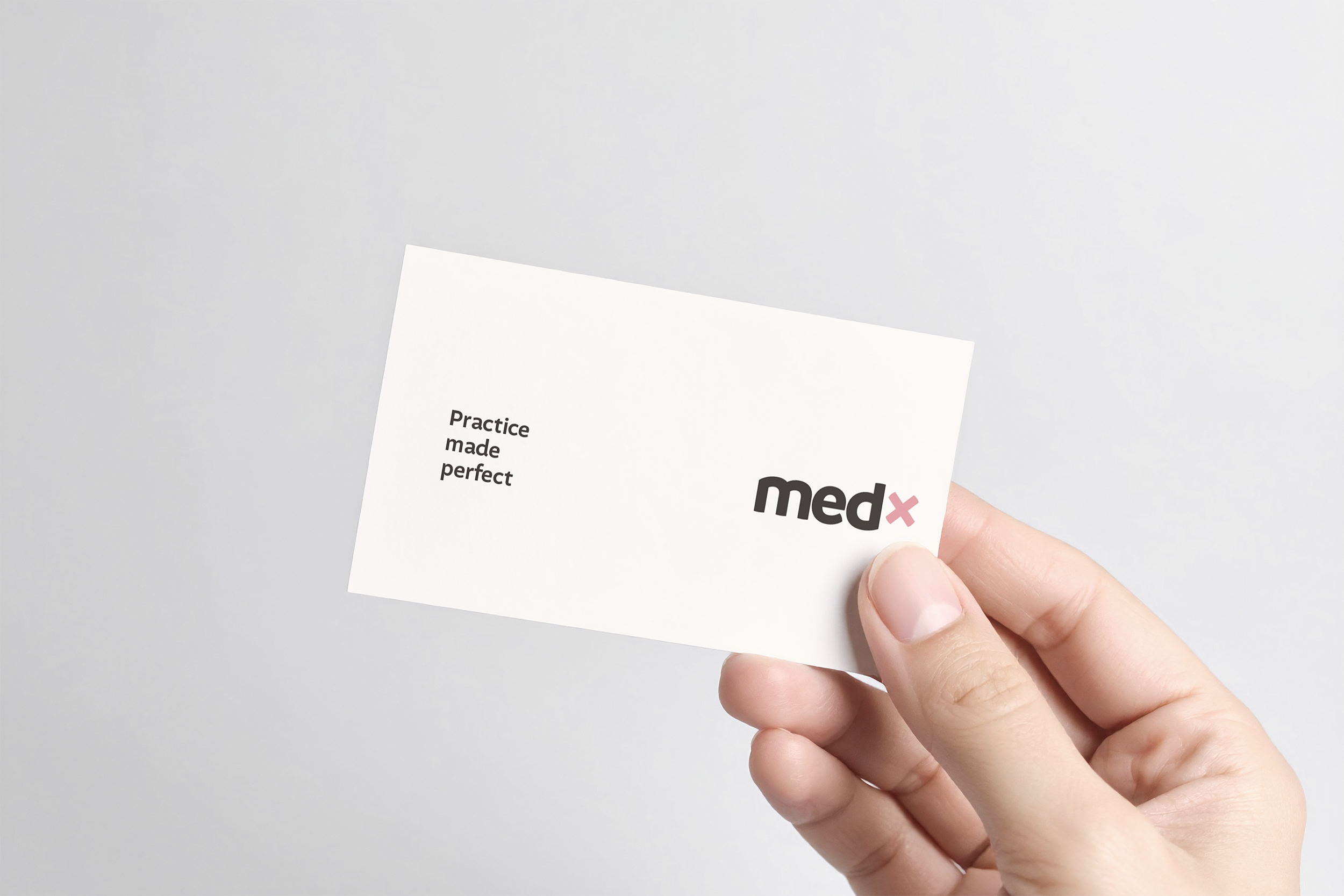 Hand holding the newly branded MedX business card on a light grey gradient background