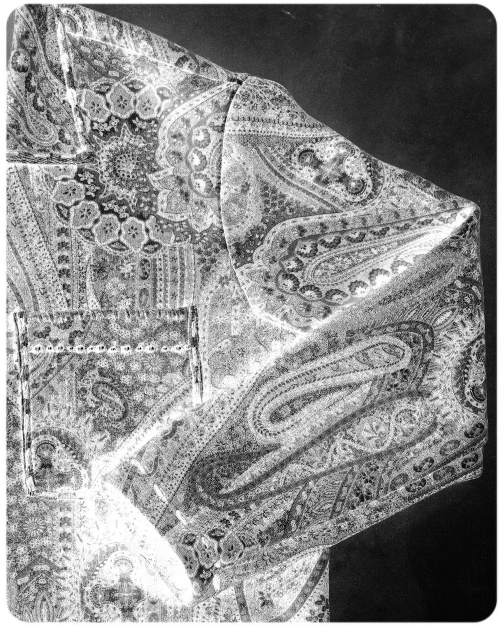 Fazzoletto di stoffa con motivi paisley e floreali, arrotolato e appoggiato su uno sfondo scuro.