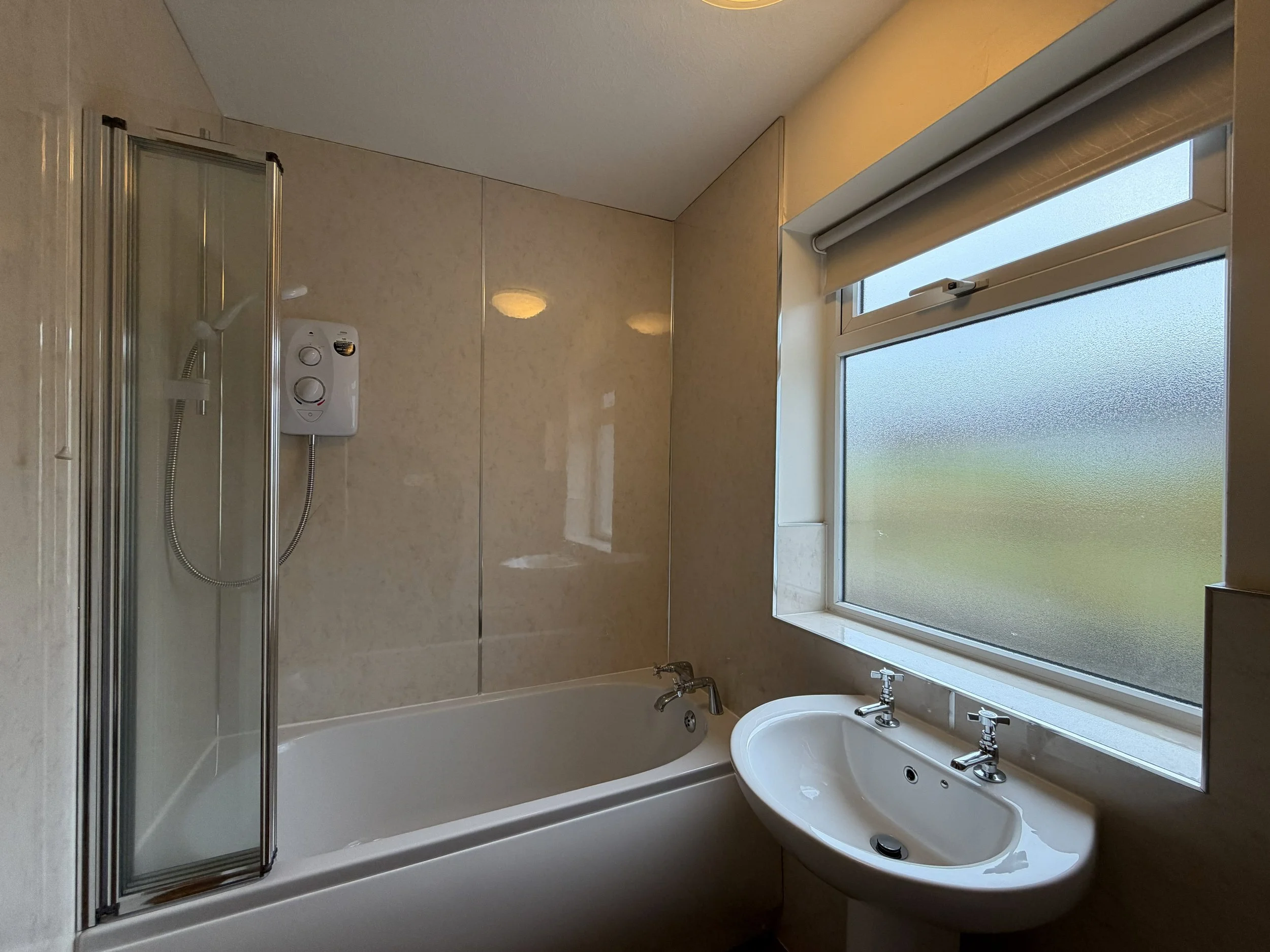 Bathroom with bathtub, shower, and sink near frosted window