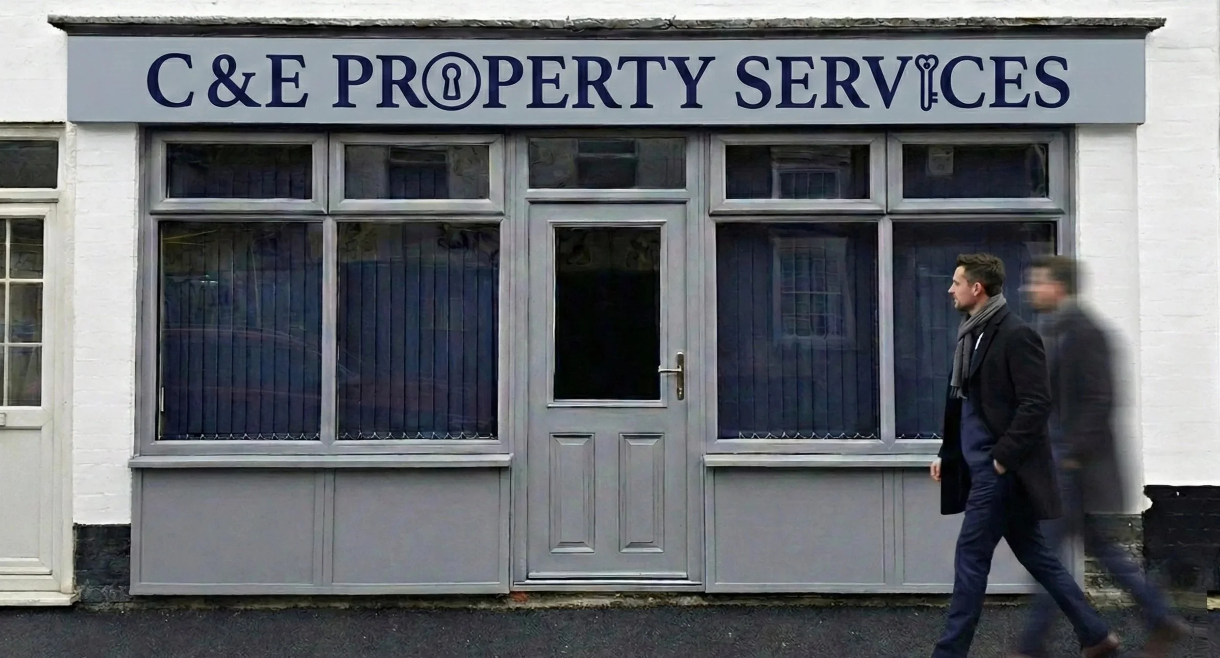 The storefront of a property services company called C&E Property Services, with a grey door and large windows, man walking past.