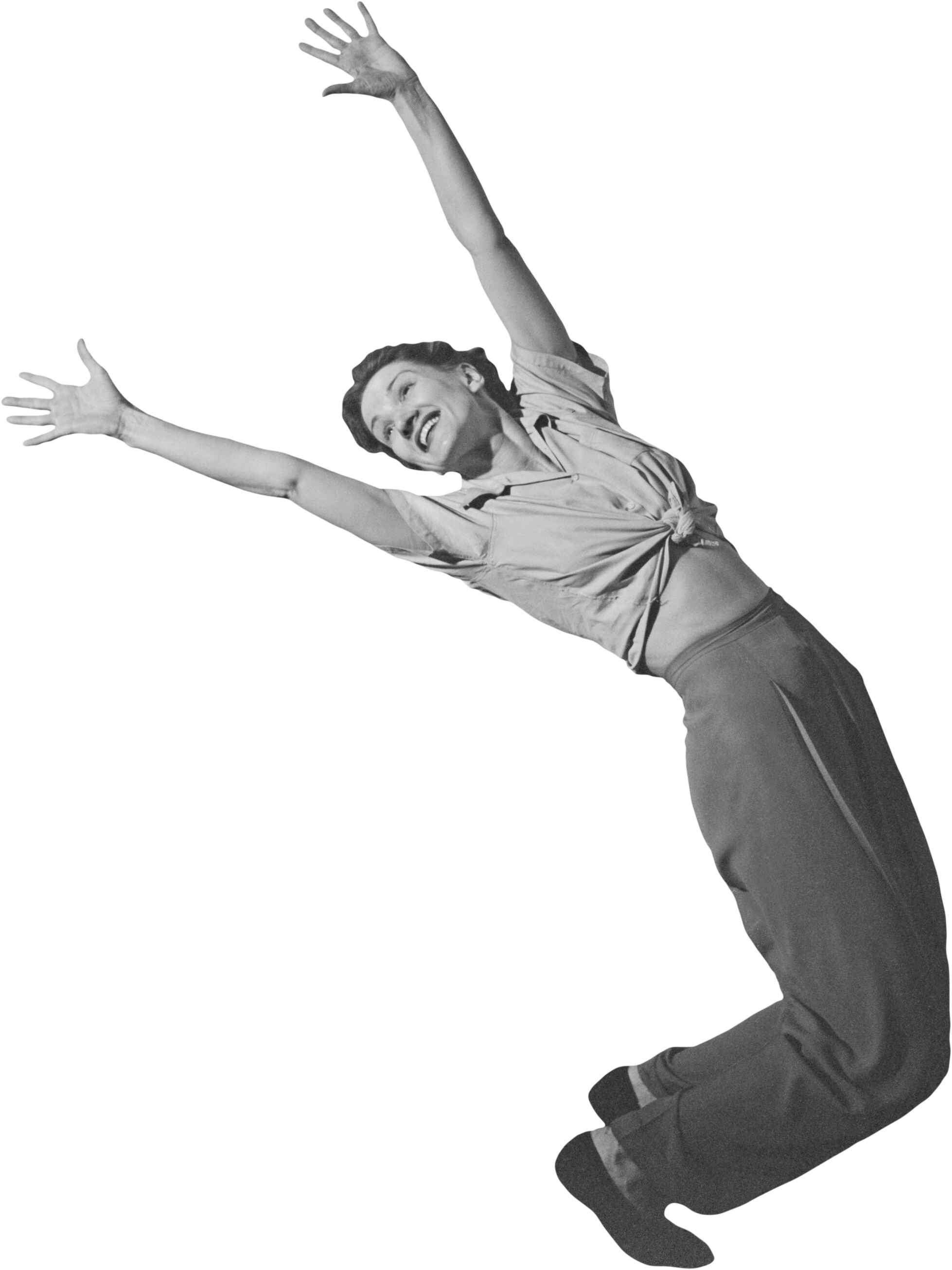 Black and white photo of a woman with short hair, smiling, wearing a tied-up shirt and loose pants, leaning back with arms raised in a joyful pose.