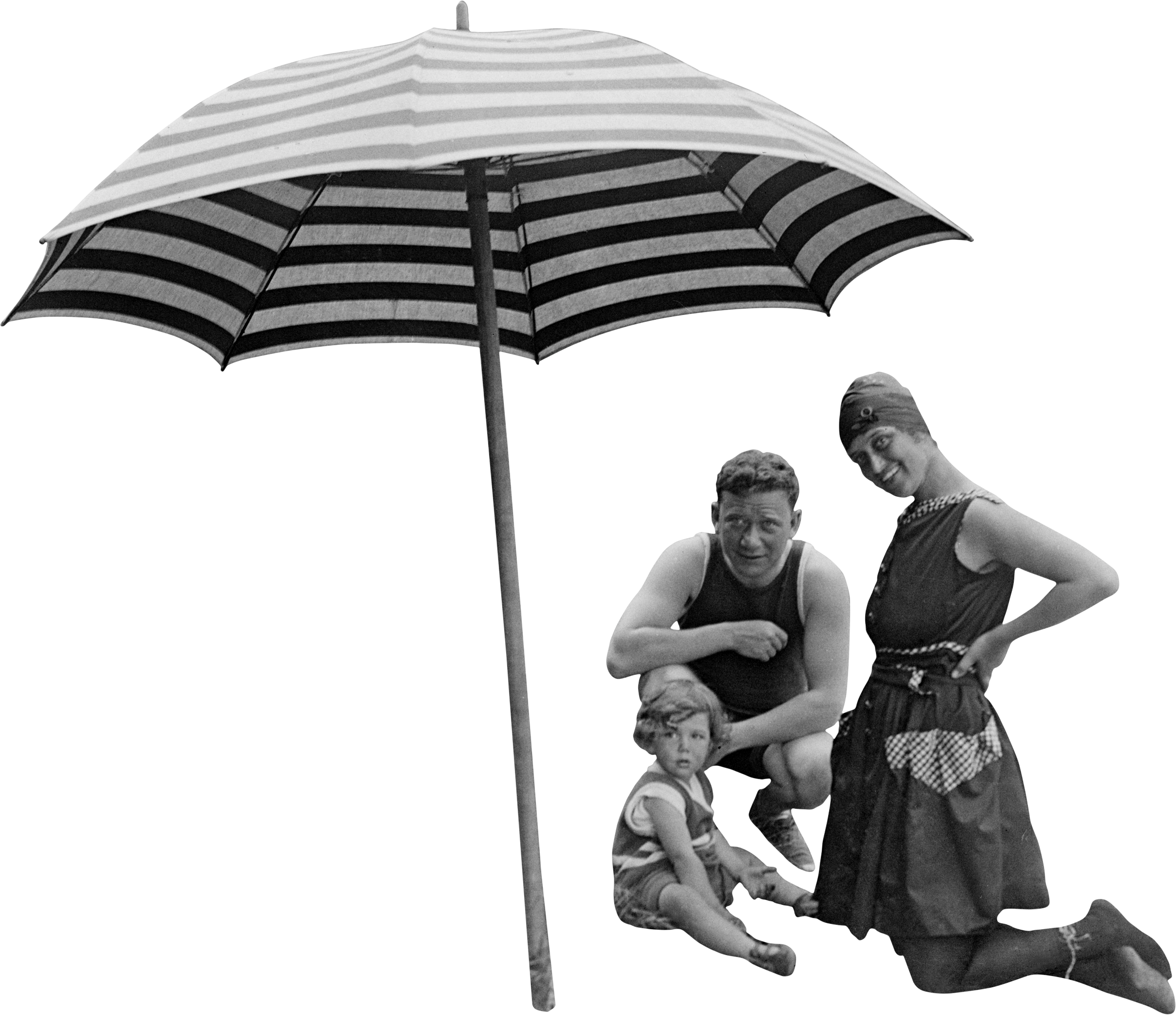 Black and white photo of a man, woman, and young girl under a large striped umbrella. The man is crouching, the woman standing with one hand on her hip, and the girl sitting on the ground.