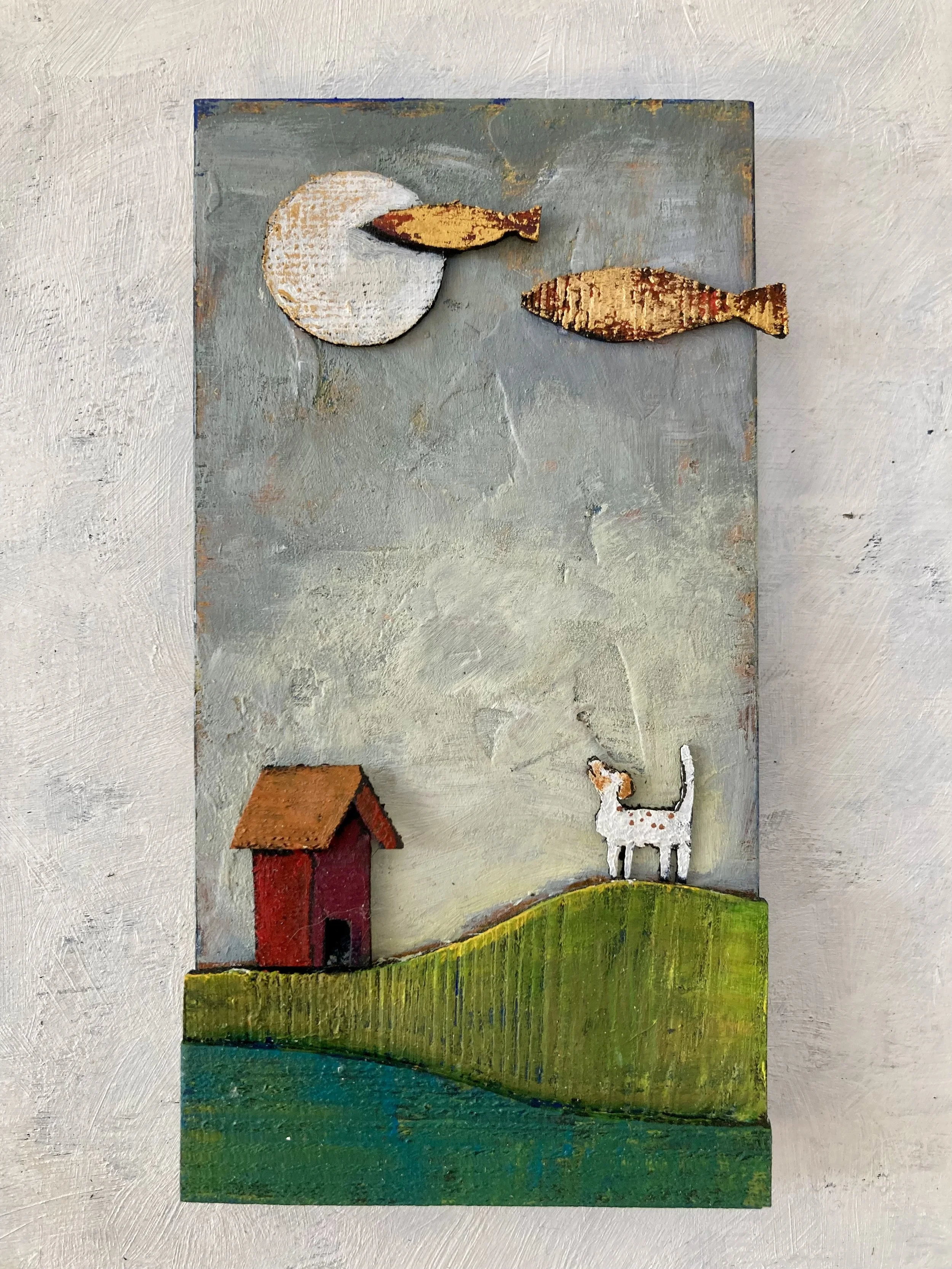 Djur- och landskapskonstverk med en hund, ett hus, två fiskar och en måne på en träram.