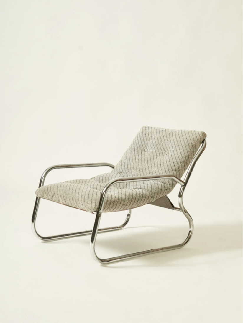 A vintage lounge chair with a metal frame and beige fabric upholstery.