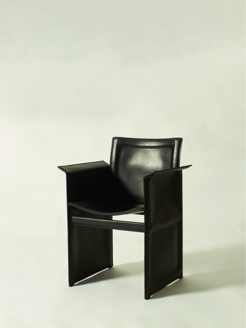 Black armchair with a modern design, featuring smooth, curved surfaces and open sides, placed against a plain light background.