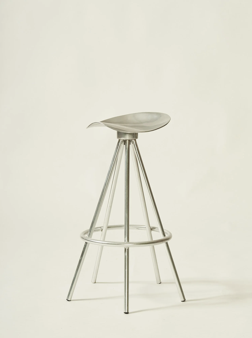 A metallic sculpture resembling a bird resting on a tripod structure, set against a plain white background.