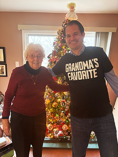Matt standing with his grandmother in front of a decorated Christmas tree