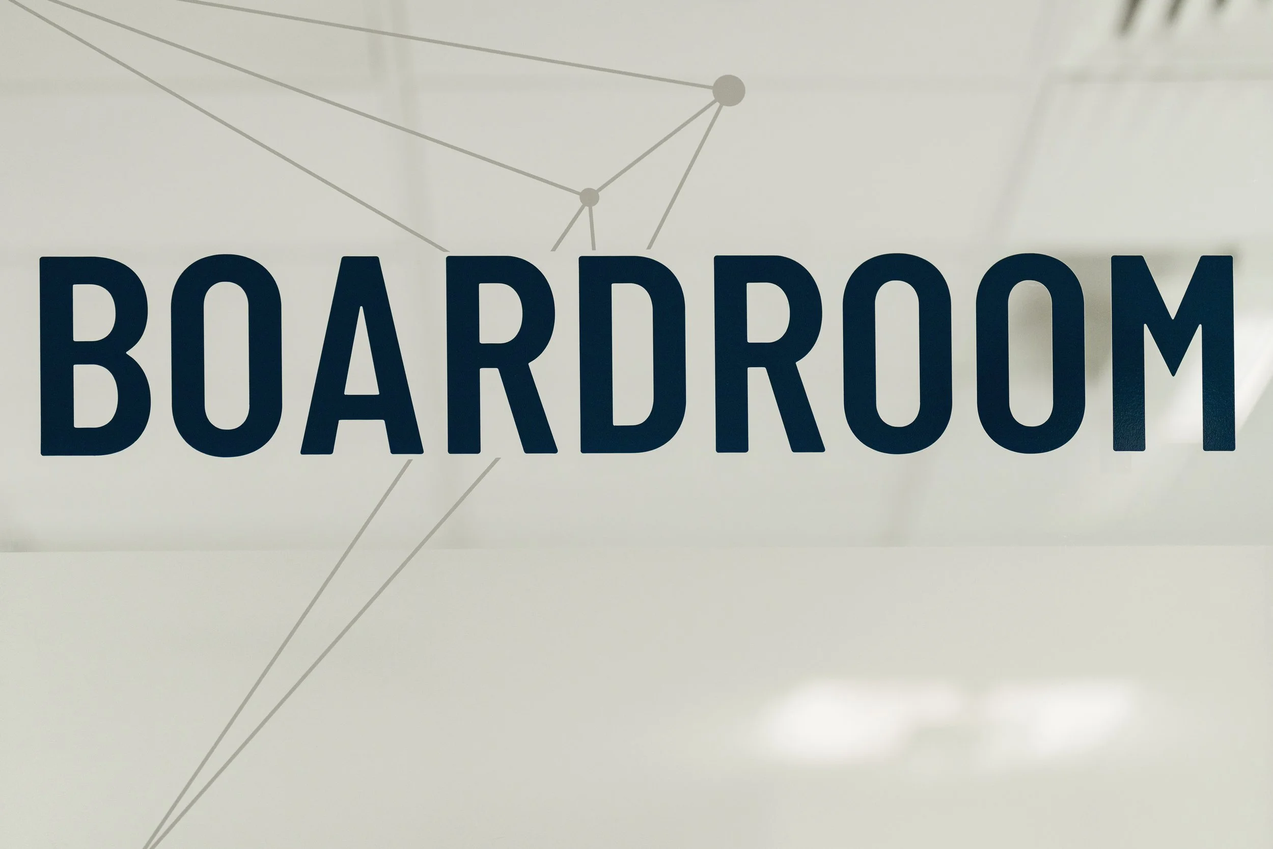 Sign with the word 'BOARDROOM' written in large black letters on a glass door or window.