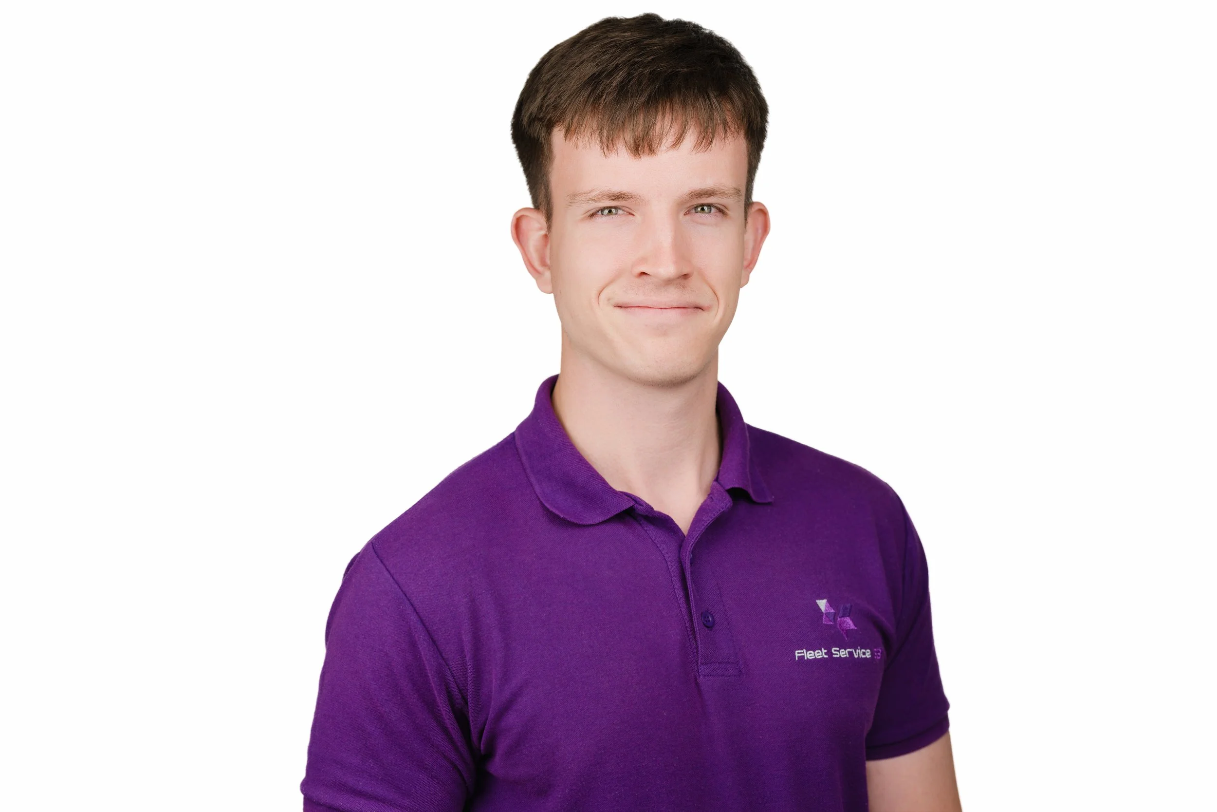 Portrait of a young man with short brown hair, wearing a purple polo shirt with a logo and text that says "Fleet Service", smiling subtly against a white background.