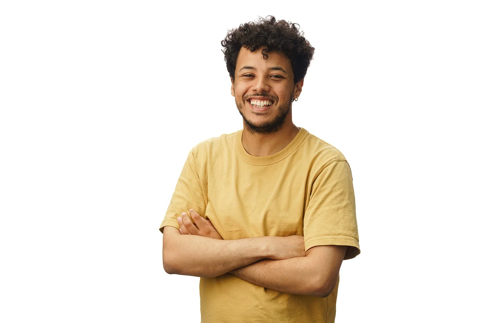 A young man with curly hair, wearing a yellow t-shirt, smiling with arms crossed against a plain white background.