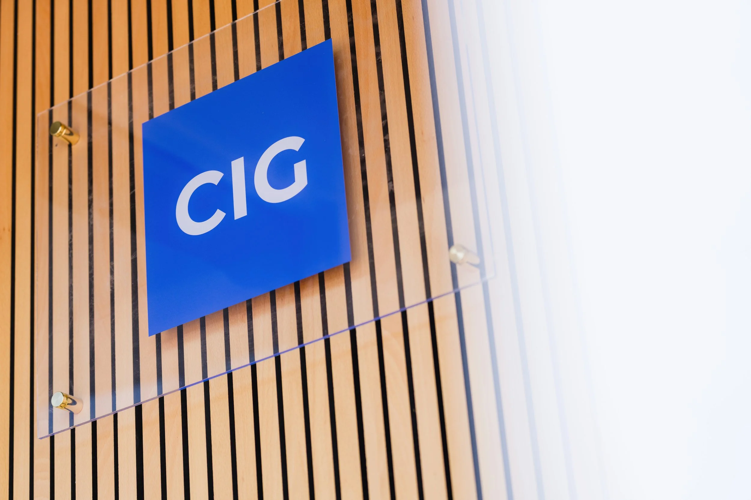 Blue sign with white text reading 'CIG' attached to wooden slatted wall.