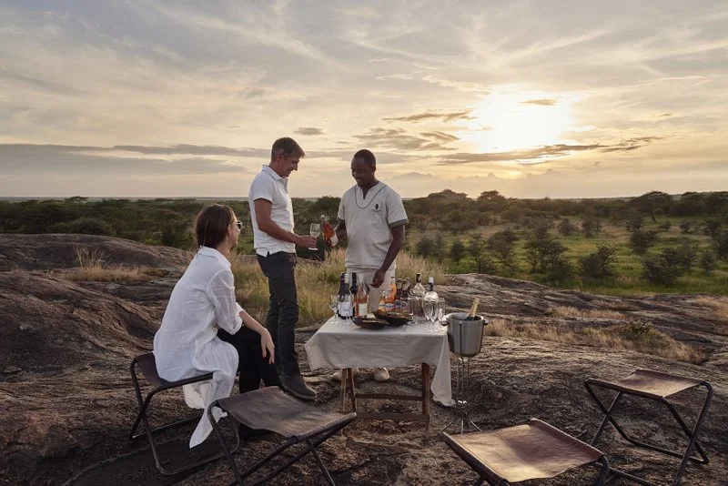 Sundowners on a boulder overlooking the Southern Serengeti, Serengeti National Park, Tanzania.