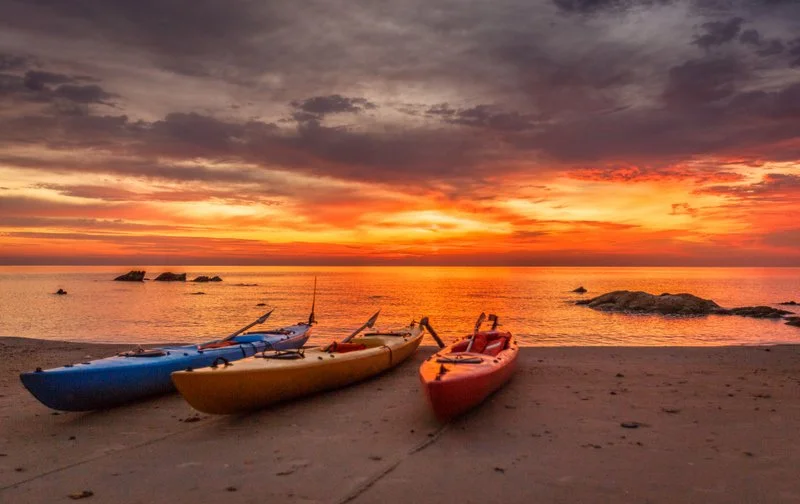 Kayaks resting on the beach of Lake Malawi at sunset after a day of adventure