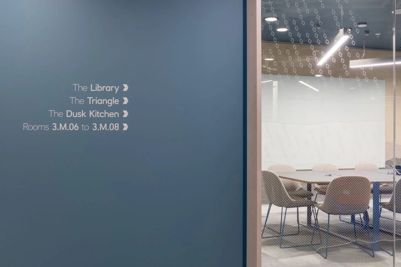 Vinyl wayfinding on blue wall and glass manifestation on glass partition