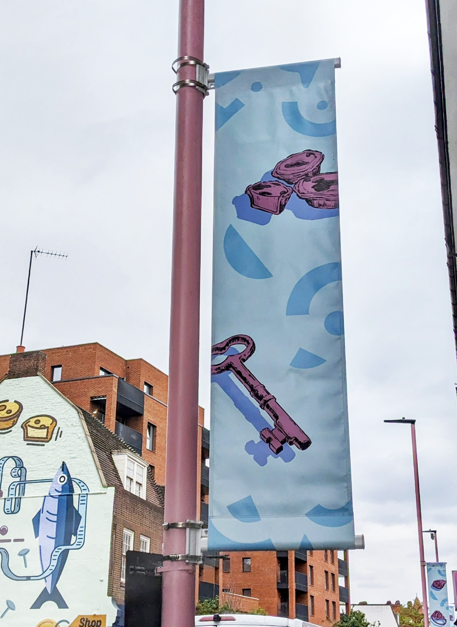 Lamp post banner with images of a key and pies