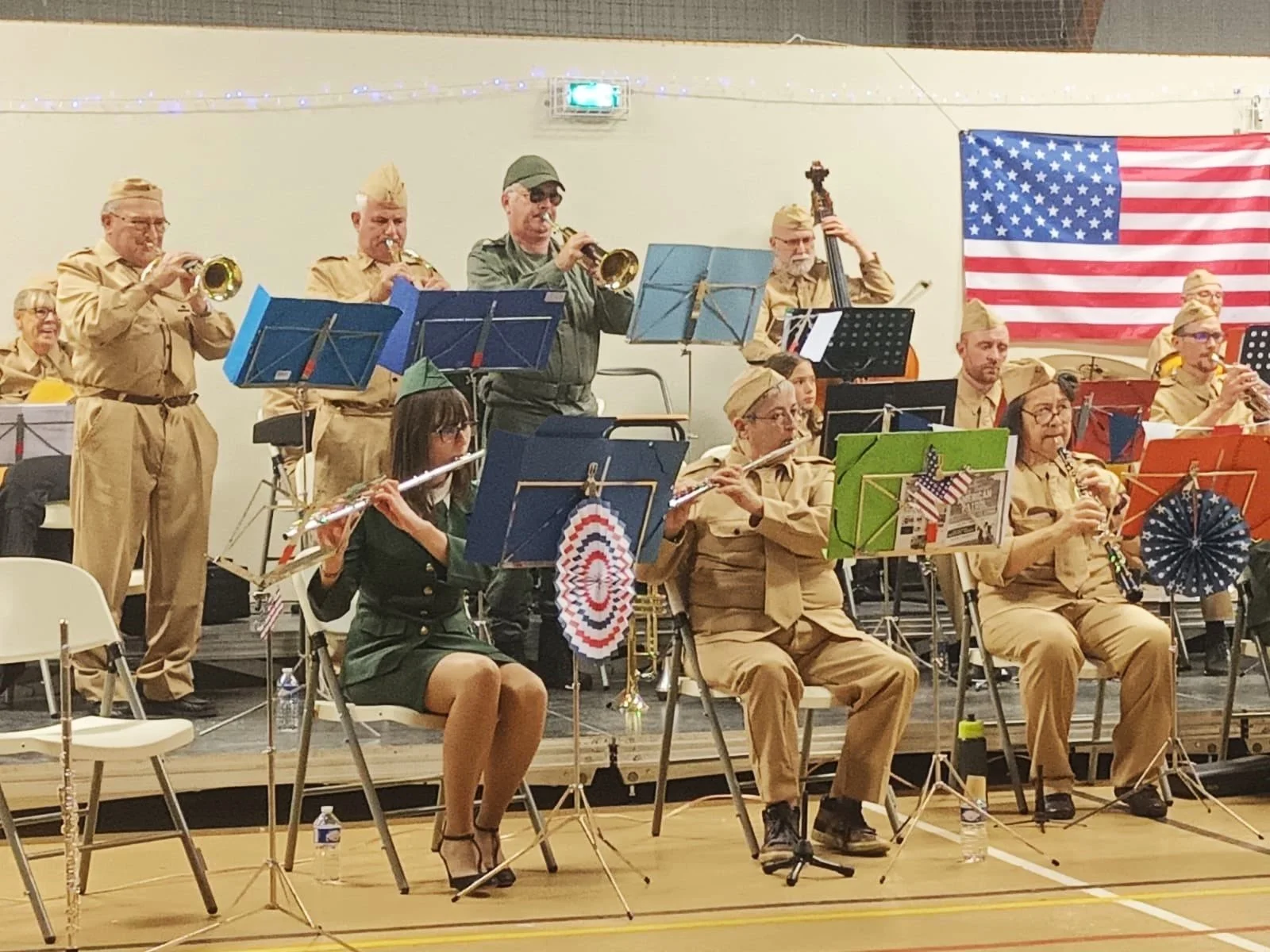 Un groupe de musiciens en uniforme jouant dans une fanfare devant un drapeau américain.