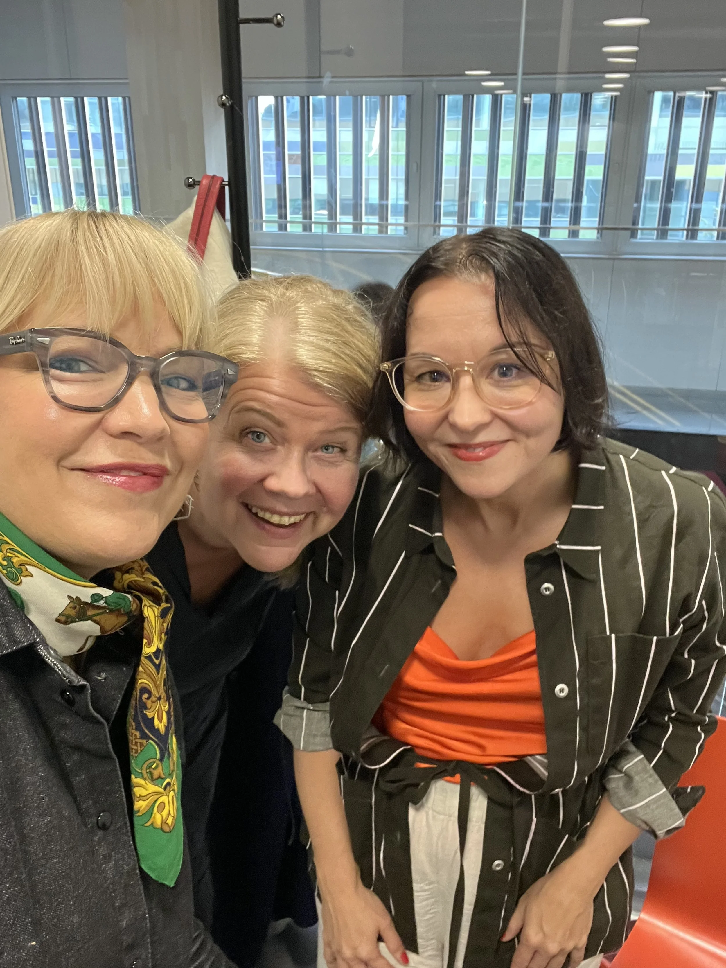 A woman with short dark hair and glasses speaking into a microphone in an office setting