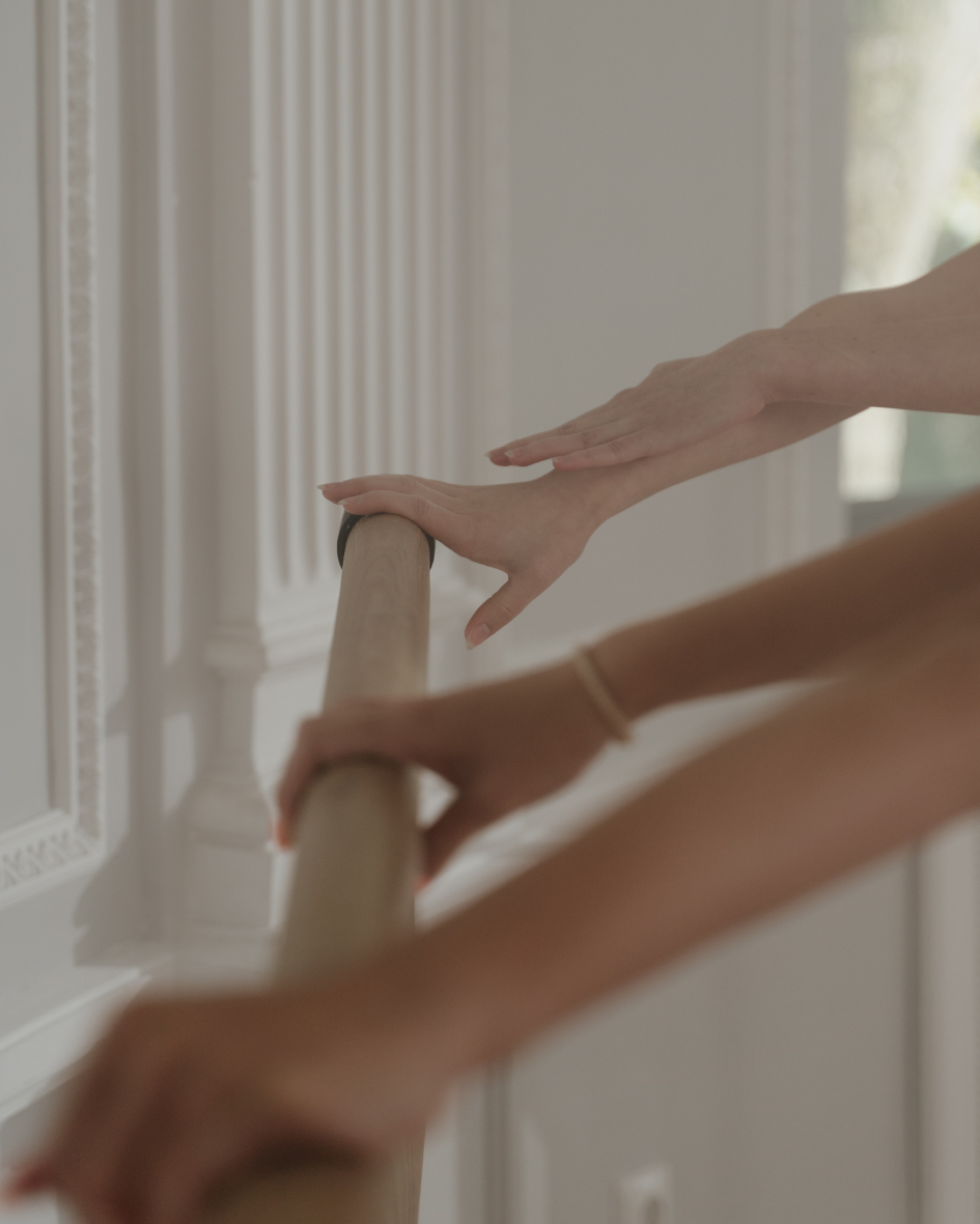 Two people holding onto a ballet barre during a dance class or practice.