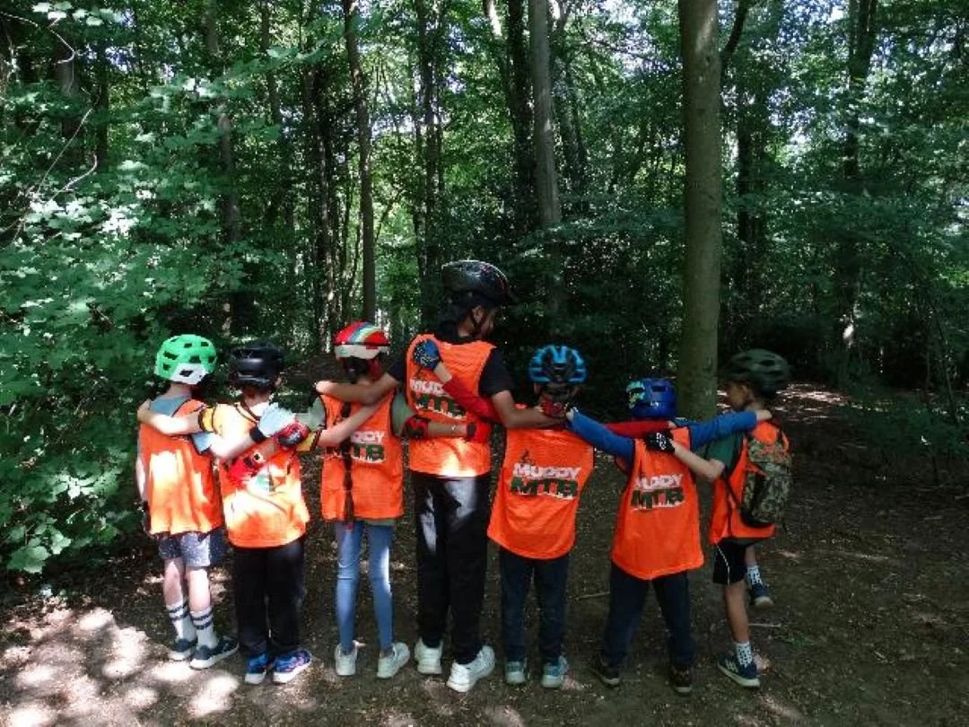 Group of young children with their arms around each other looking into the forest