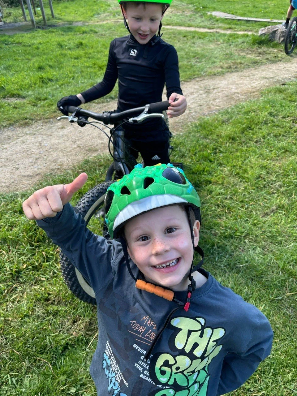 Two children smiling and looking at the camera after a mountain bike riding session