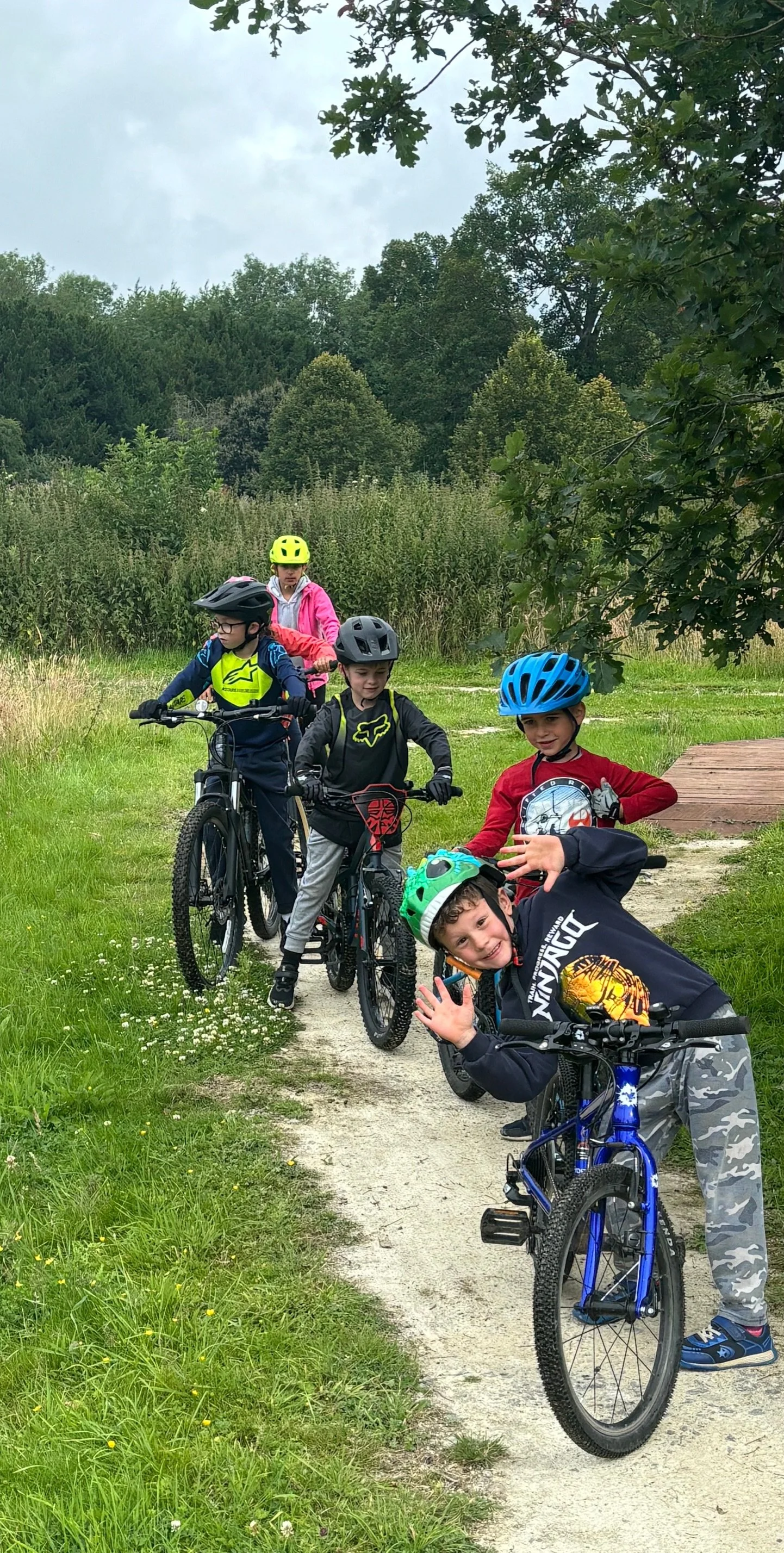Children smiling and waving to the camera on their bikes