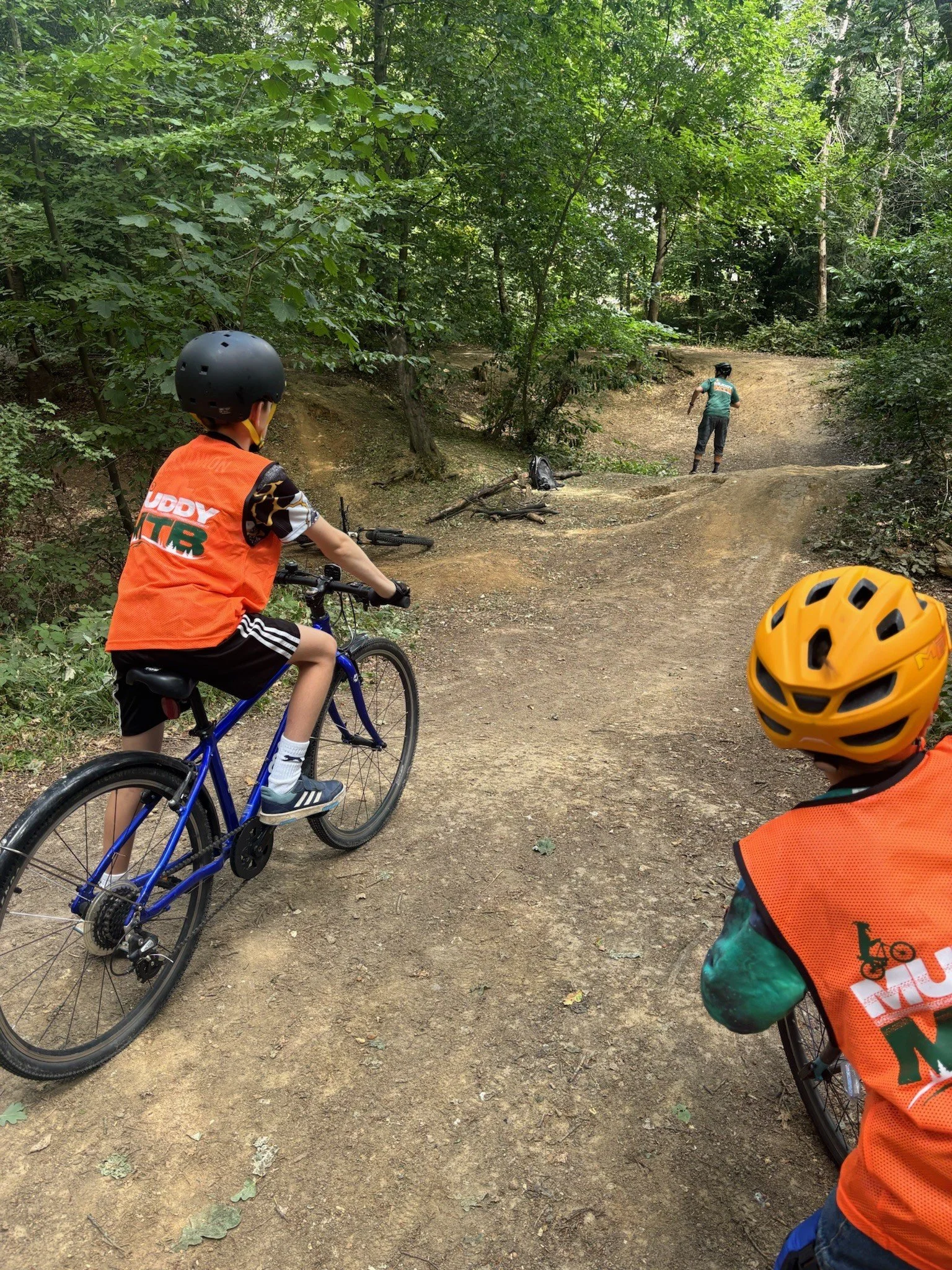 Two children on mountain bikes tackling natural berms in woodland 