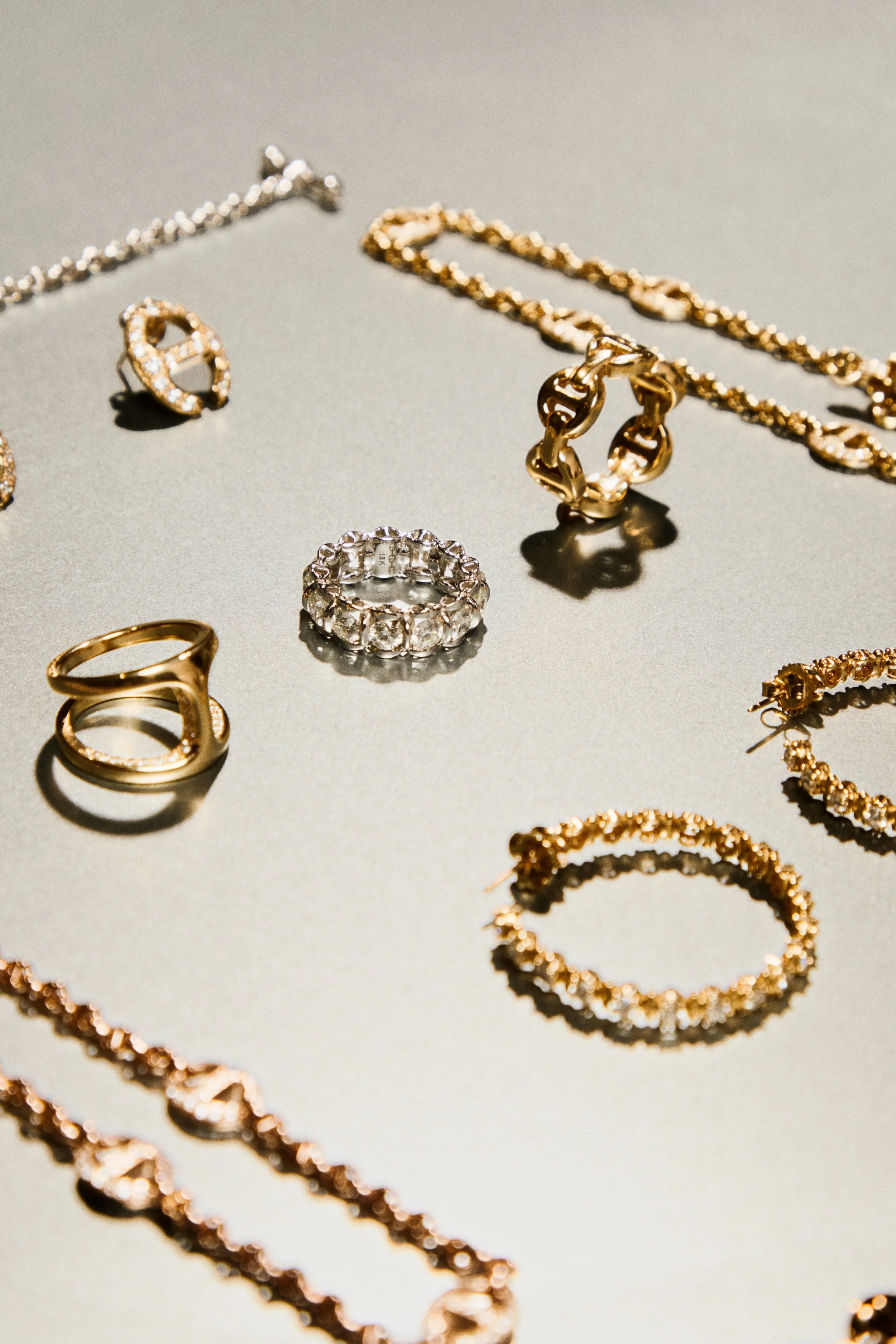 Various pieces of jewelry including rings, necklaces, and bracelets laid out on a reflective surface.