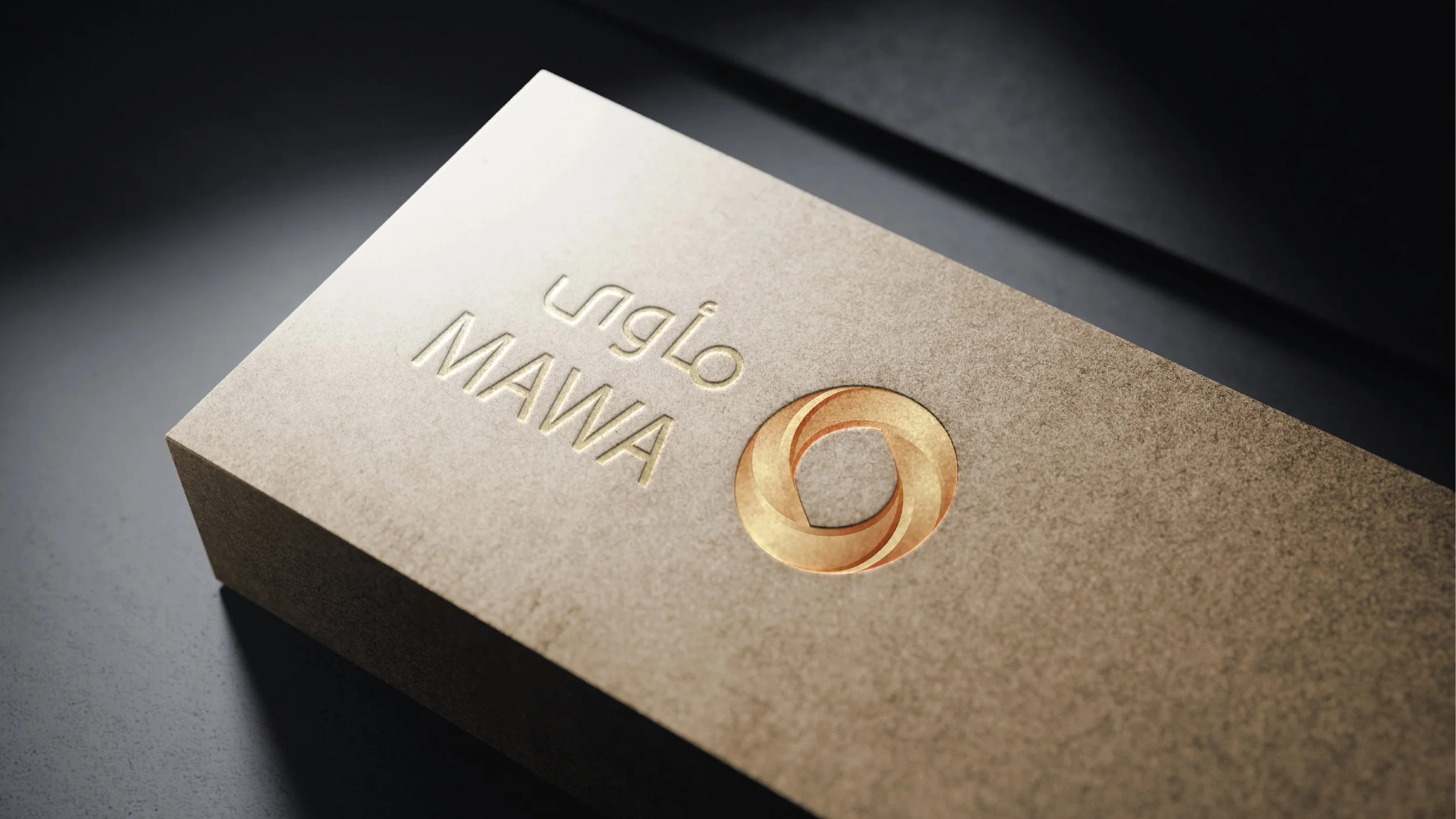 A beige box with embossed text and a gold logo on top, placed on a dark surface.