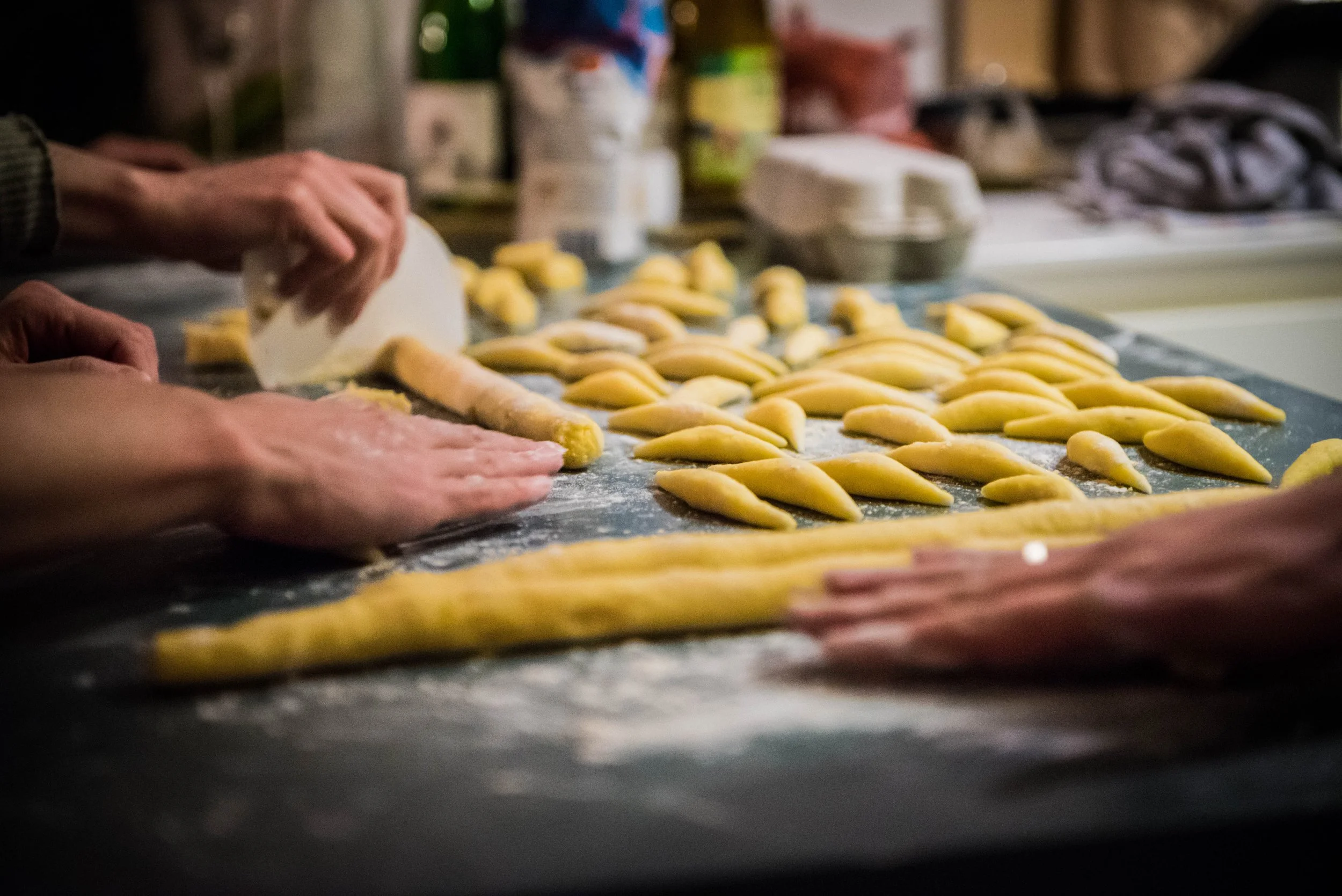 Hände formen frische Teiglinge auf einer bemehlten Arbeitsfläche