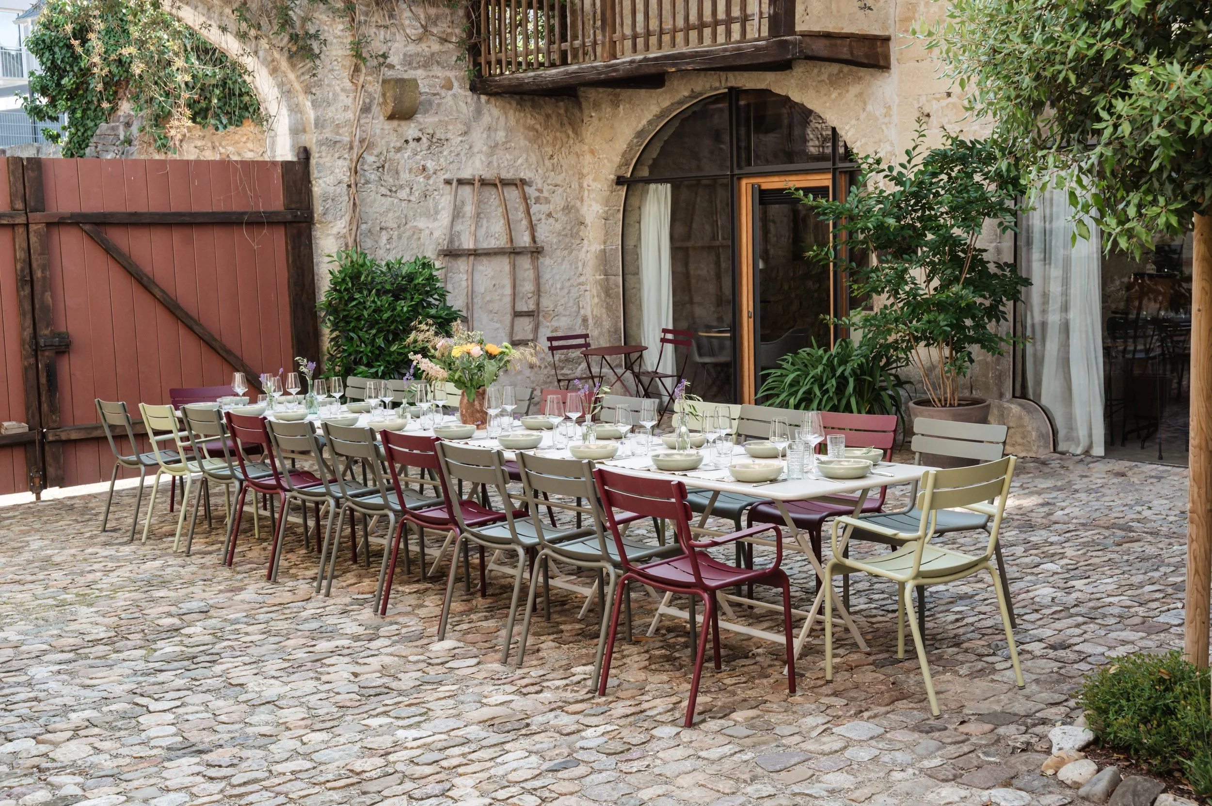 Ein langer Tisch mit gedecktem Geschirr und Gläsern in einem historischen Innenhof.