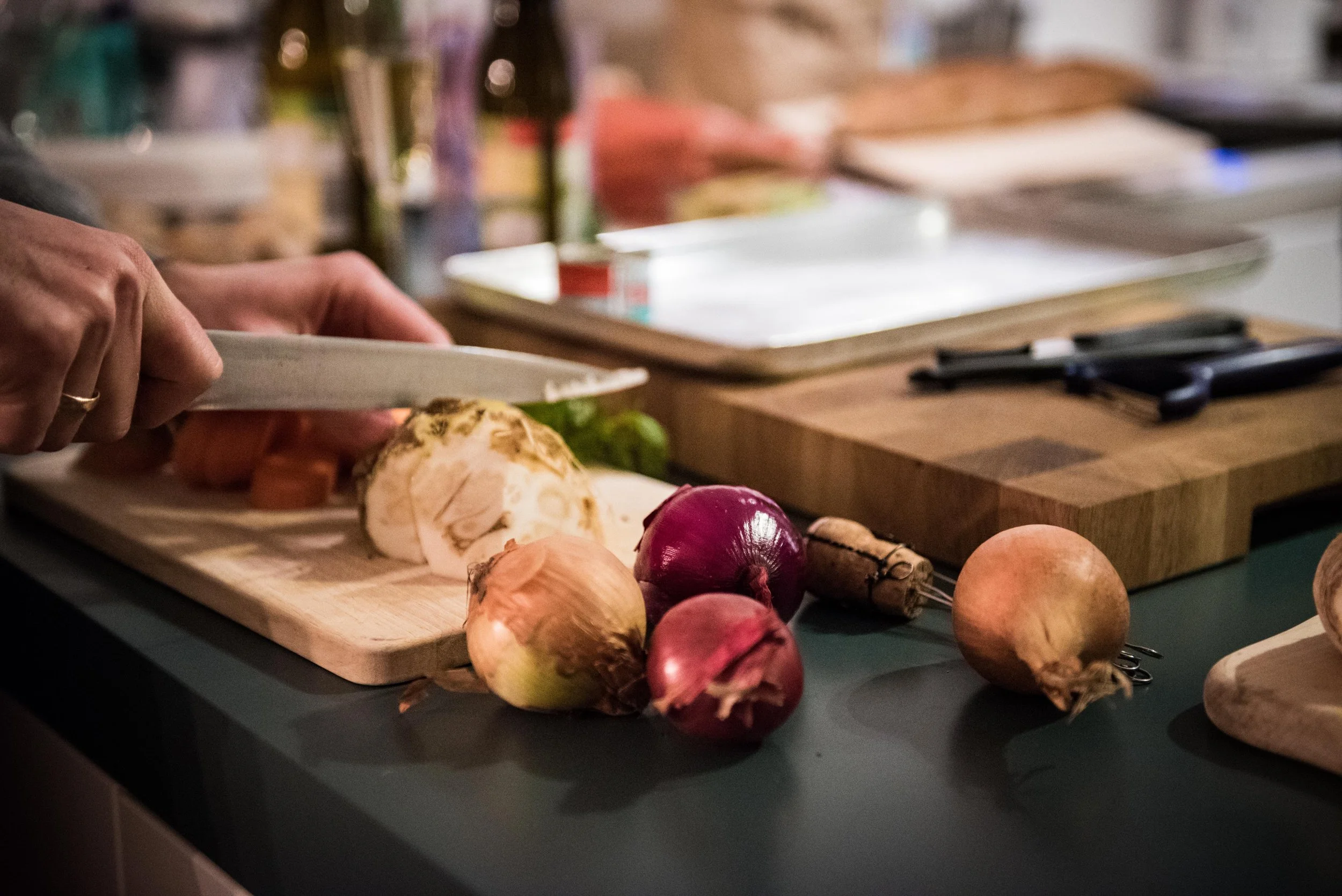 Person schneidet Zwiebeln und andere Gemüse auf einem Küchenbrett.
