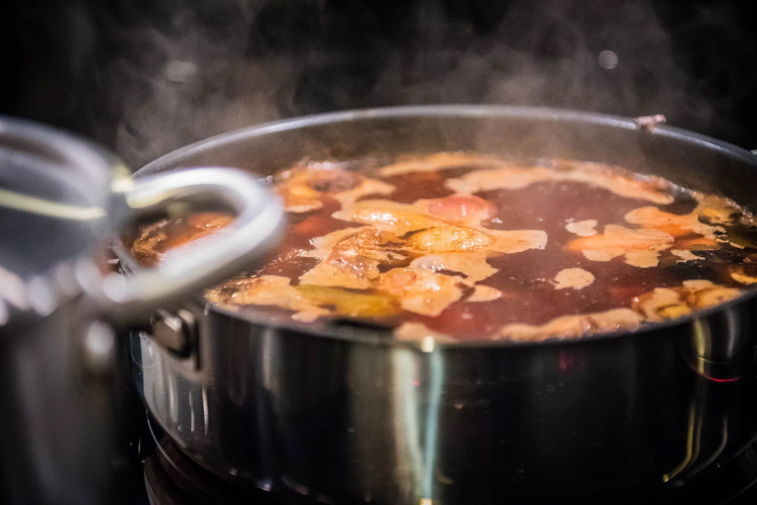 Eine braune Sauce in einem Topf köchelt auf einem Herd.